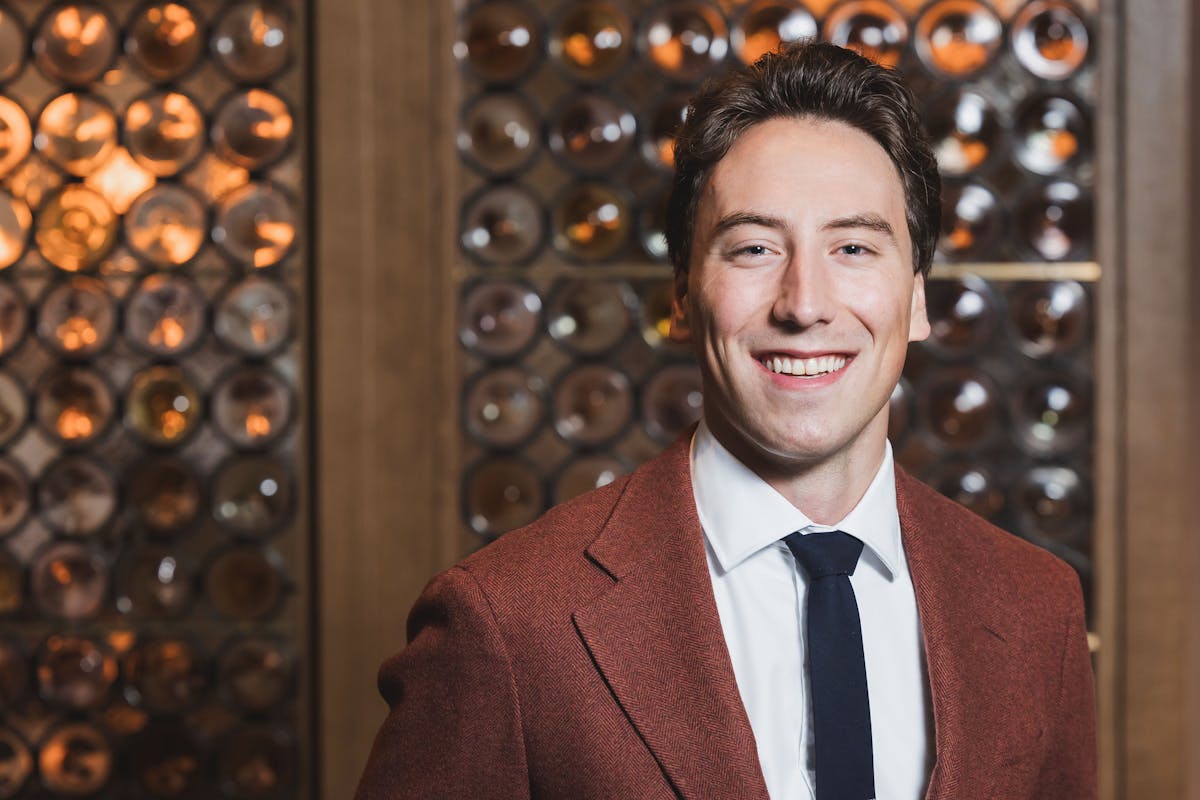 a man wearing a suit and tie smiling at the camera