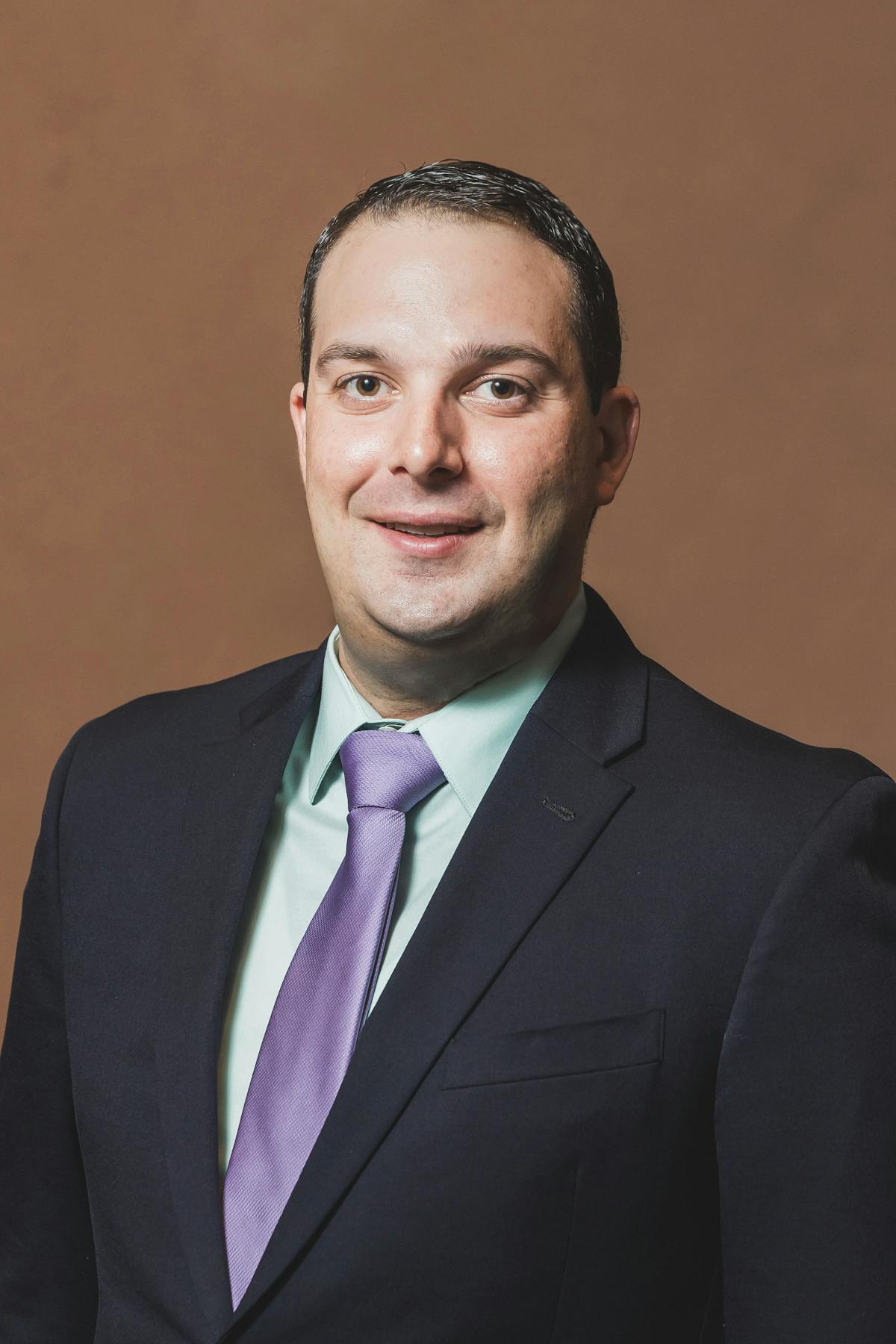 a man wearing a suit and tie smiling and looking at the camera
