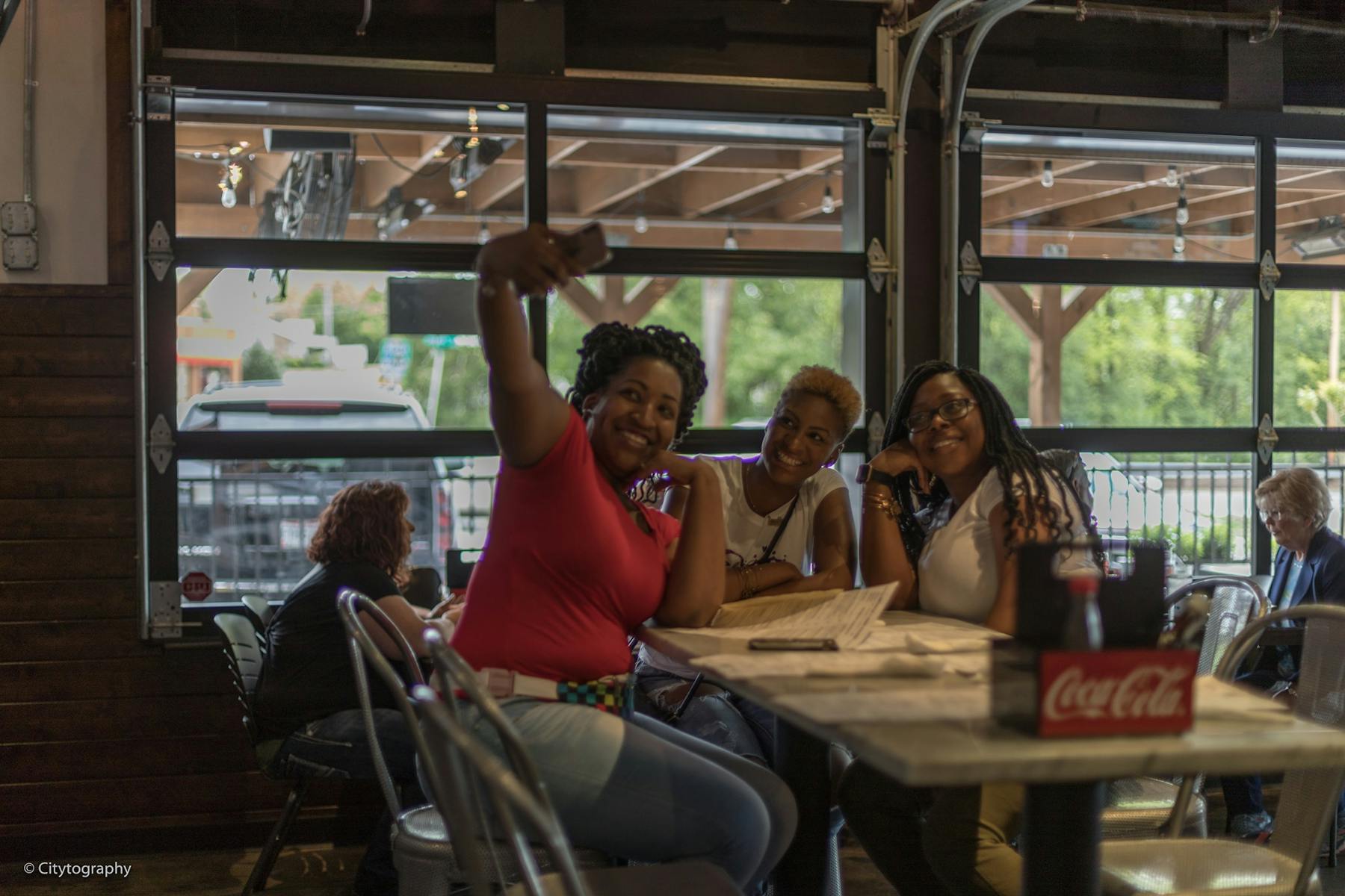 a group of people sitting at a table in front of a window taking a pciture