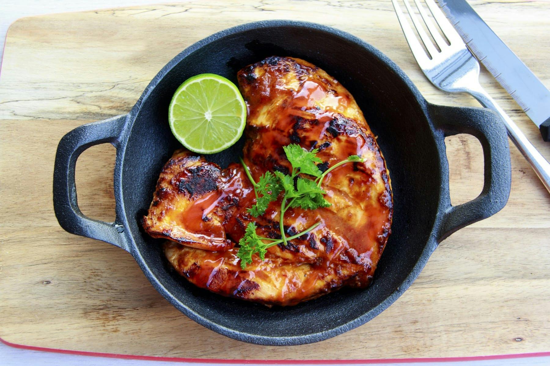 chicken on a frying pan sitting on top of a wooden table