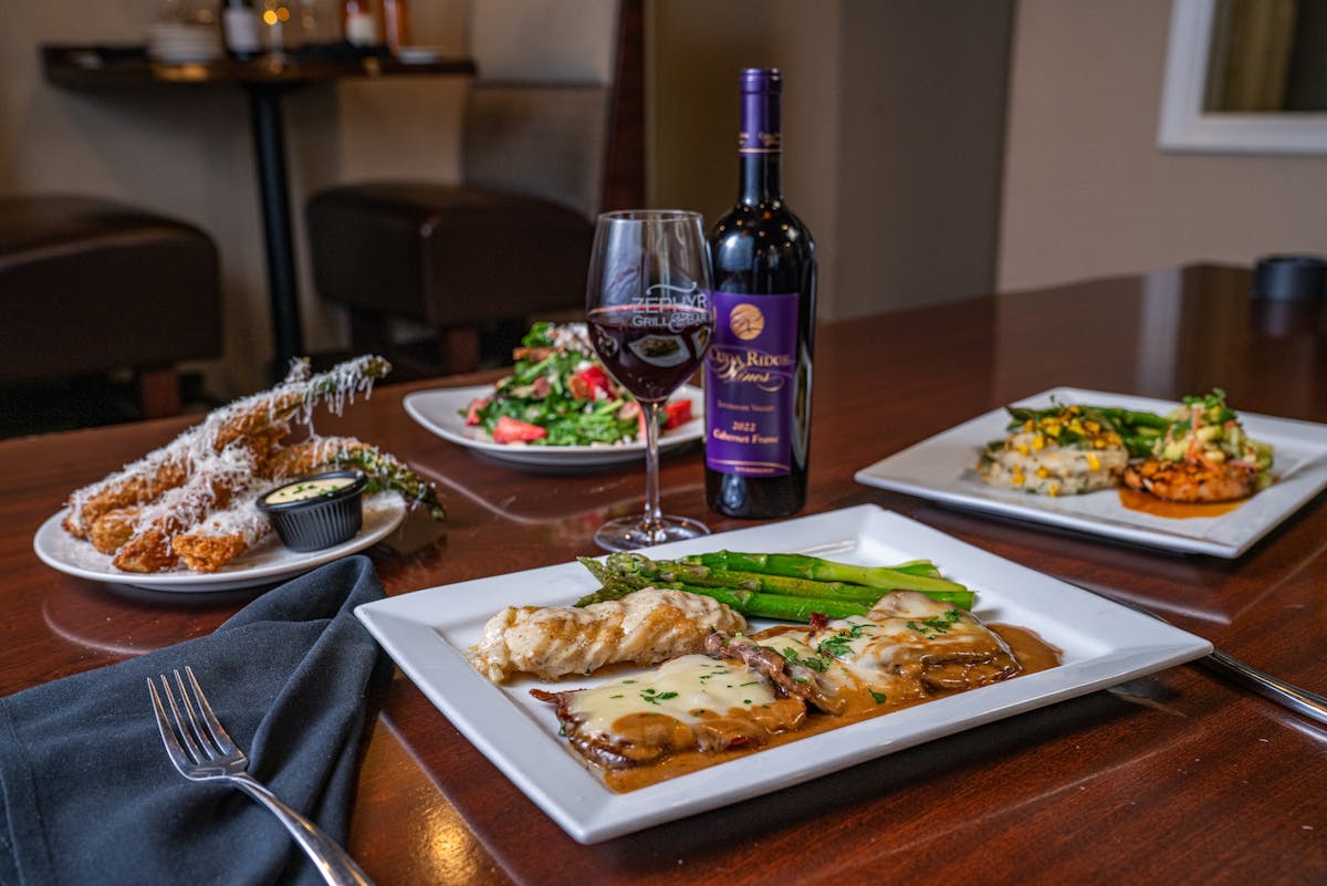 various plated food on a table with a bottle and glass of wine