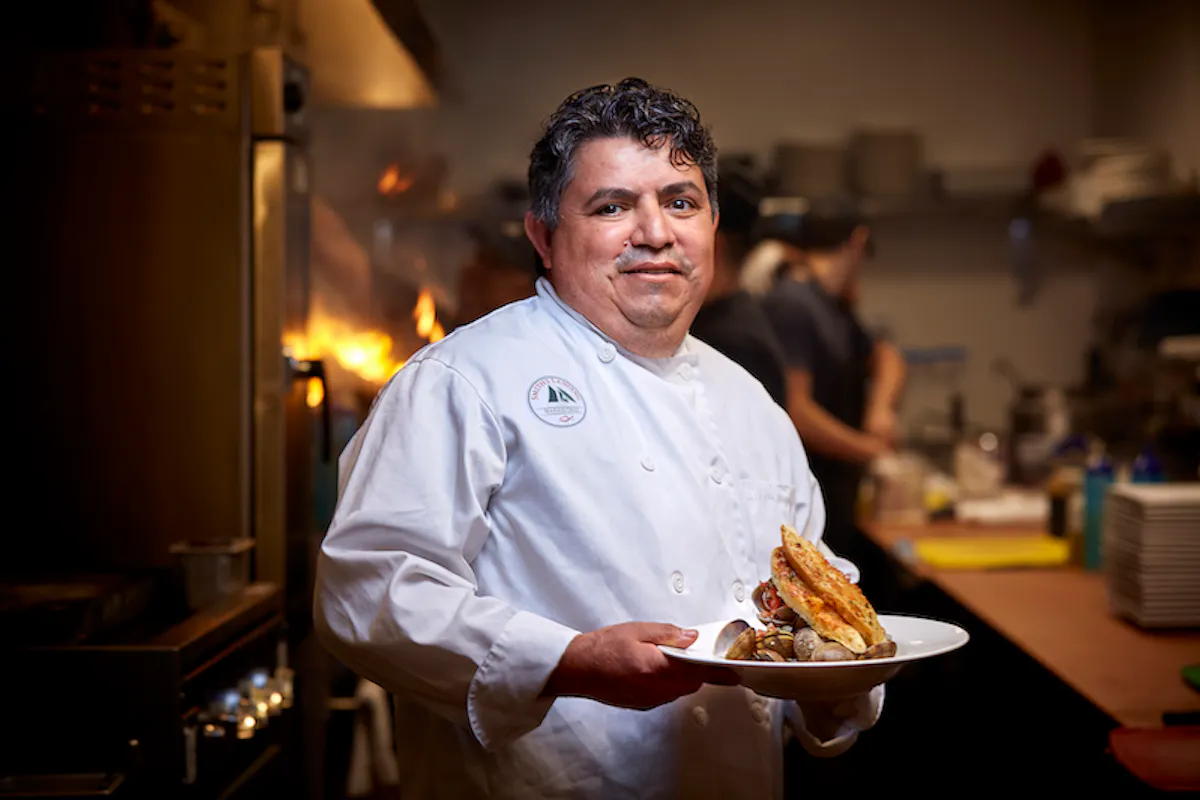 a man holding a plate of food on a table