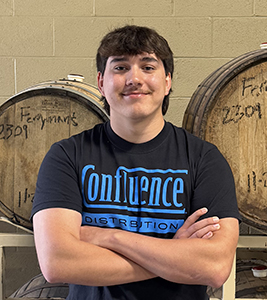 a man with arms crossed in front of barrels