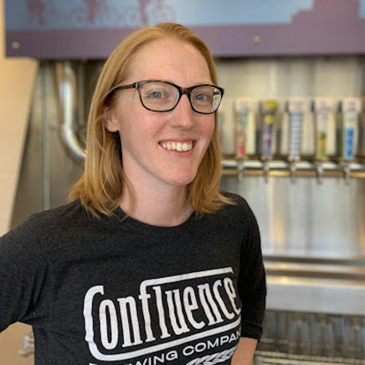 a person wearing glasses and smiling at the camera