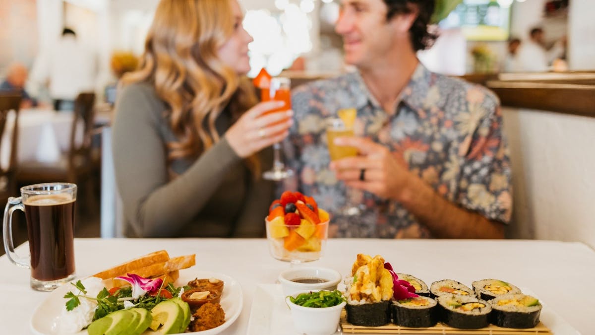 a man and woman sitting at a table with food