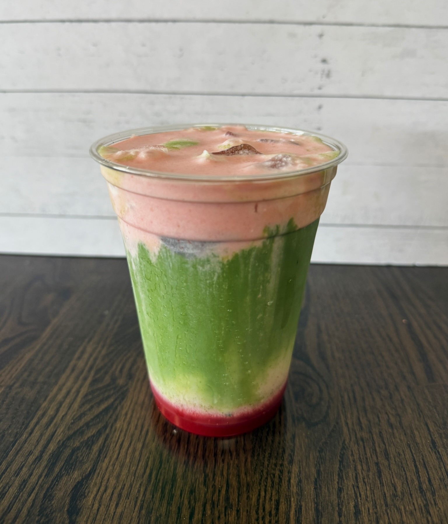 a green and red drink in a plastic cup
