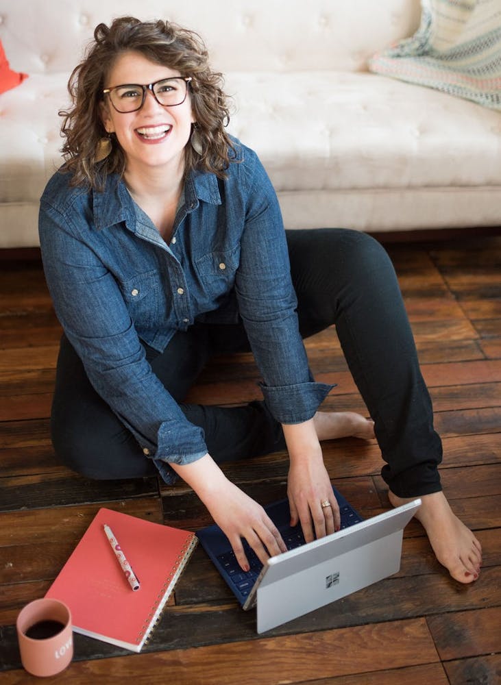 a woman sitting on the floor smiling at the camera