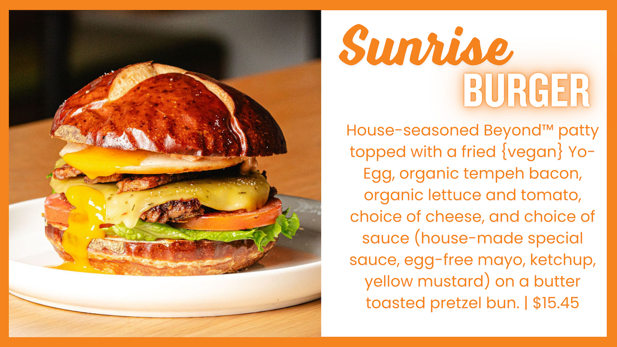 A close-up of the Sunrise Burger on a plate, featuring a house-seasoned Beyond™ patty, fried (vegan) Yo-Egg, organic tempeh bacon, organic lettuce and tomato, melted cheese, and choice of sauce, all on a butter-toasted pretzel bun. The right side of the image contains a text box with the burger’s description in green font, framed by a green border, emphasizing its plant-based ingredients.