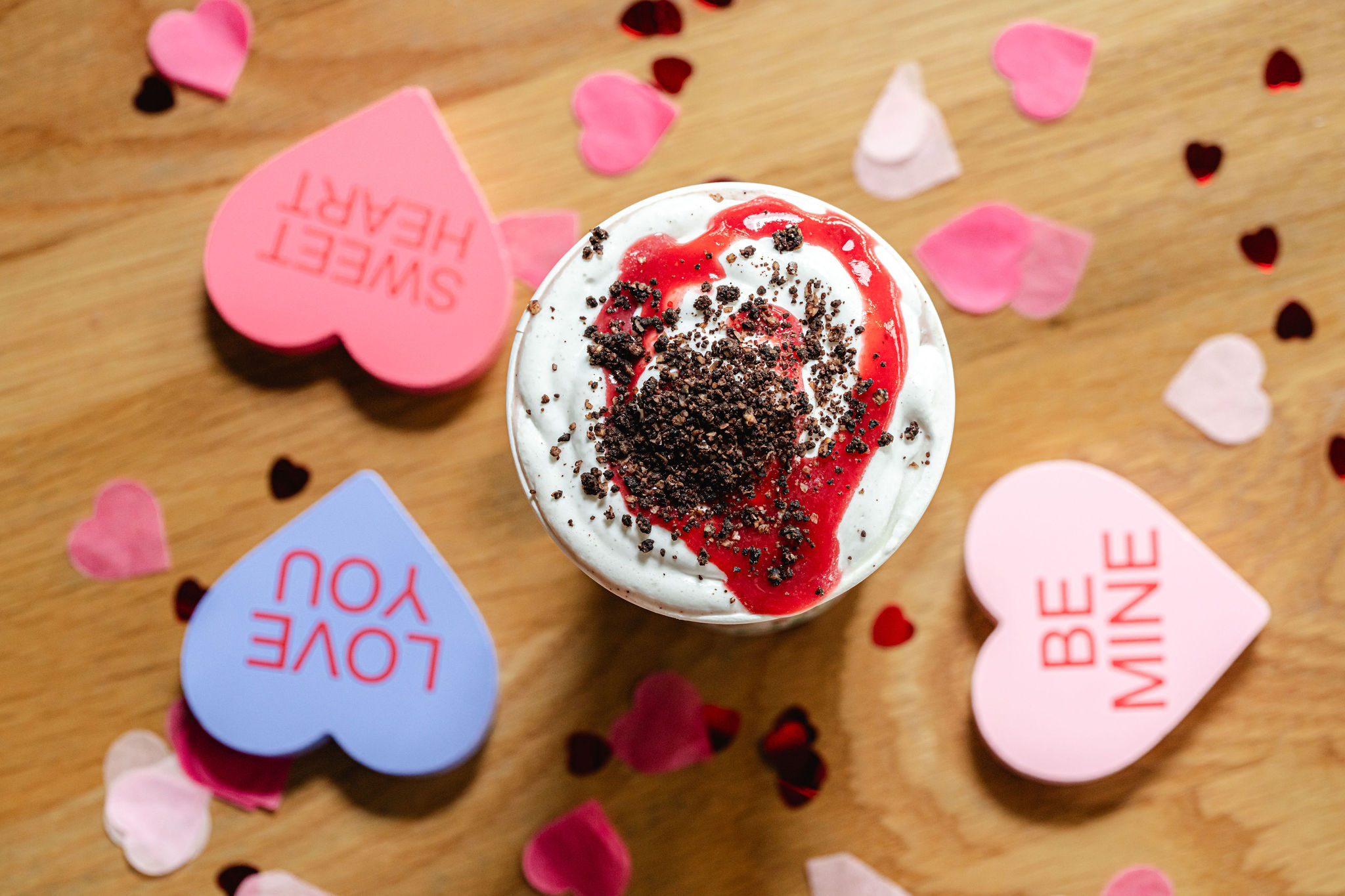 Organic Strawberry Cookies & Cream Shake with whipped cream, cookie crumbles, and strawberry puree in a branded cup with heart-themed designs
