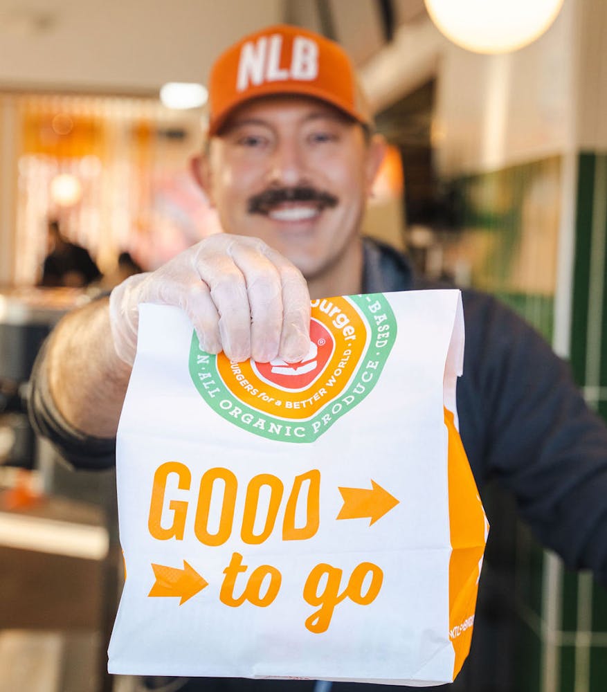 a man smiling with a to-go bag in a restaurant curbside pick-up window