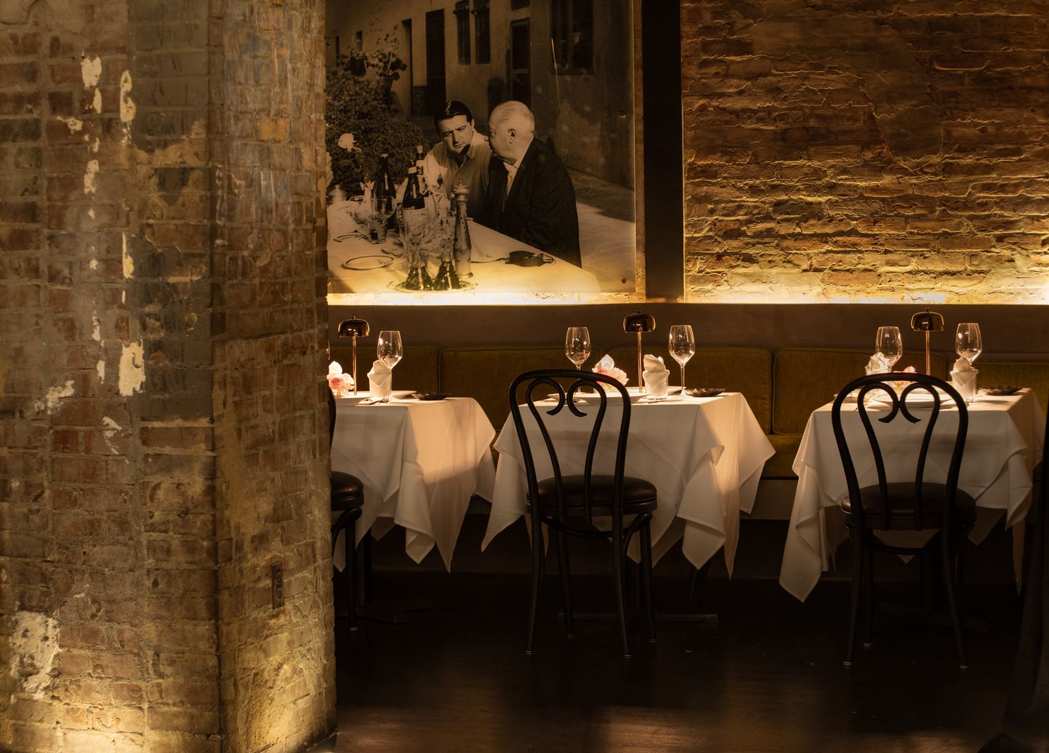 Warm private dining room at Tucci NYC with exposed brick, white tablecloths, and candlelit ambiance