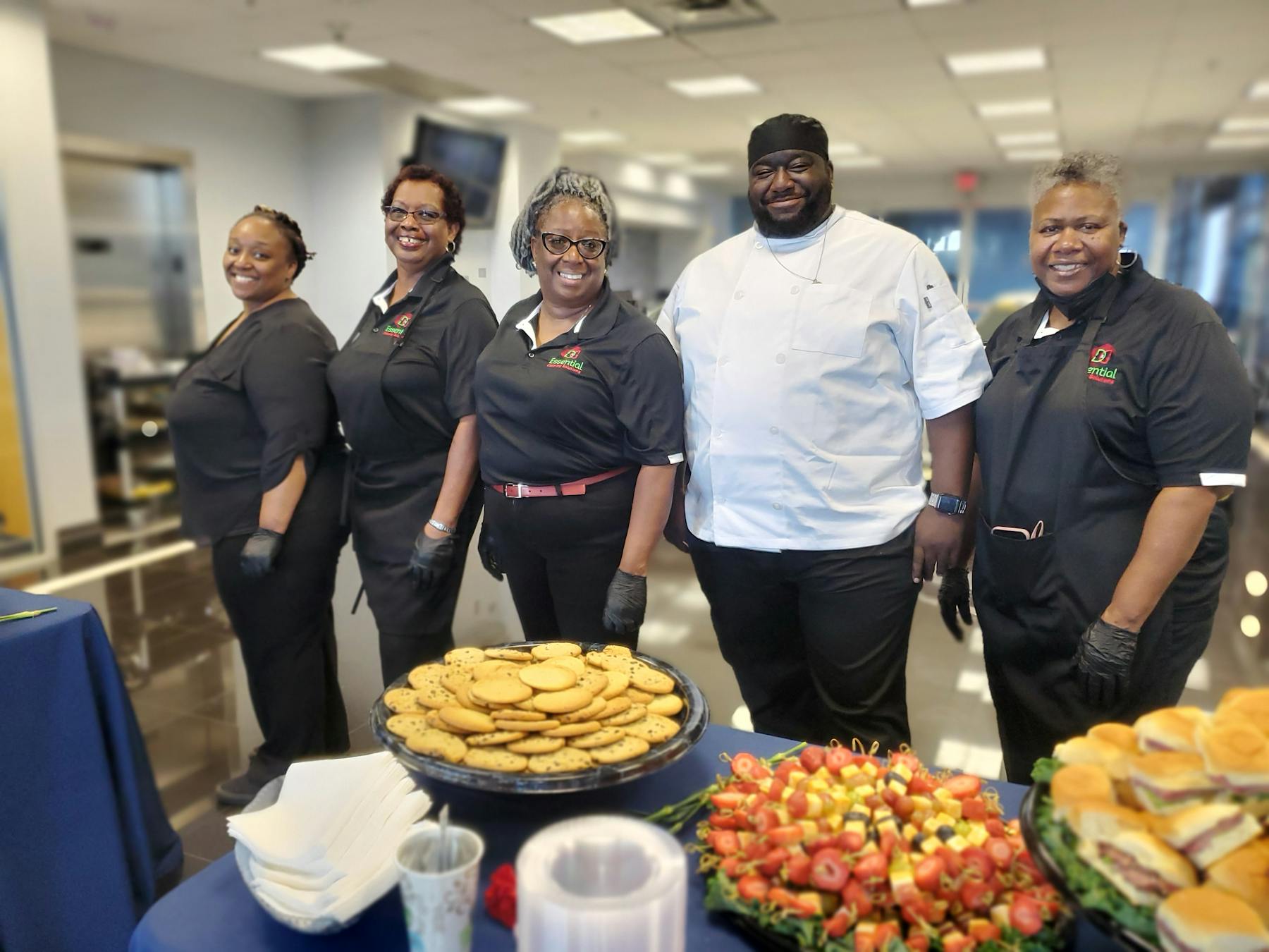 a group of people standing around a table full of food