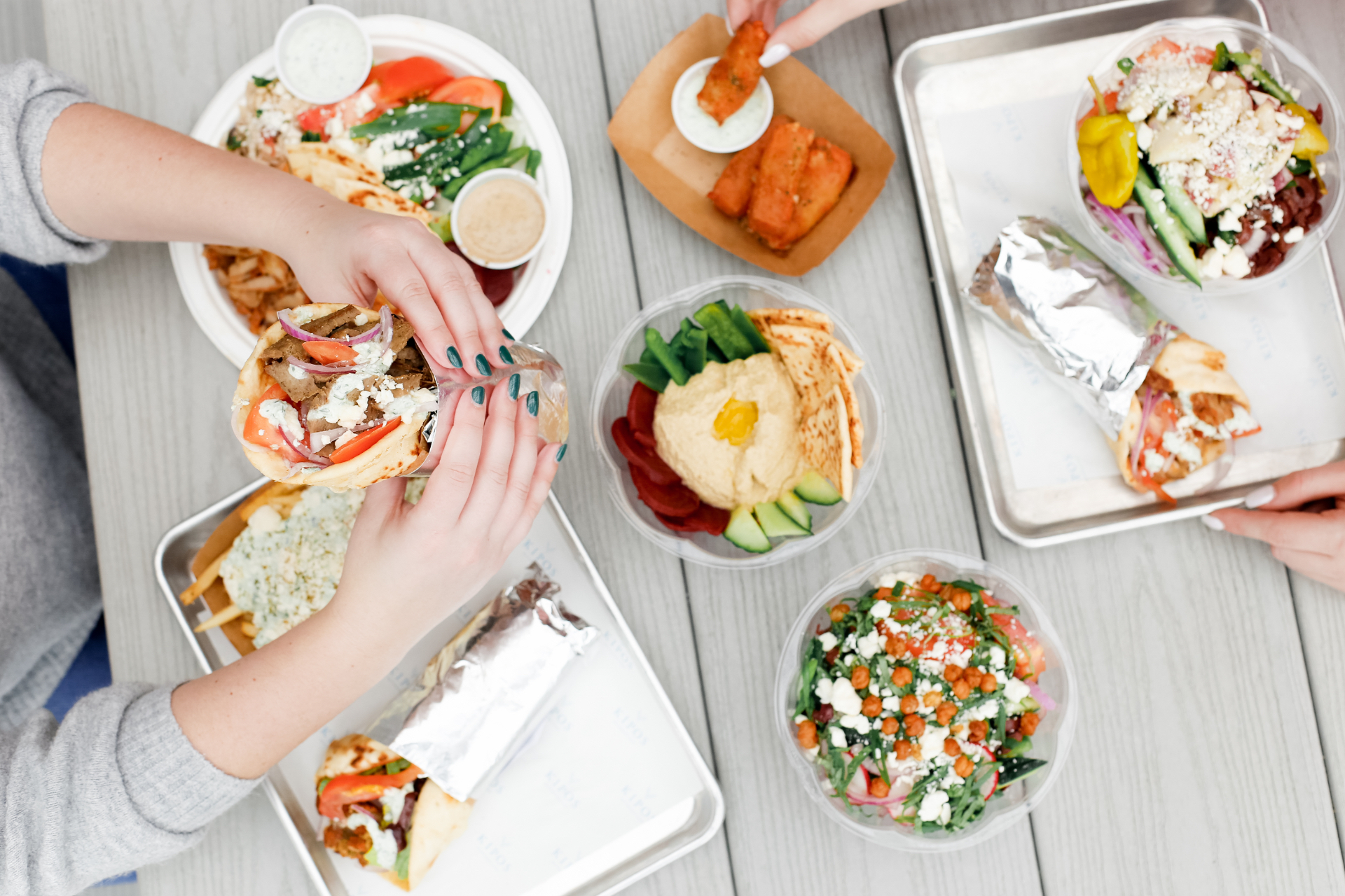 a woman holding a bunch of food on a table