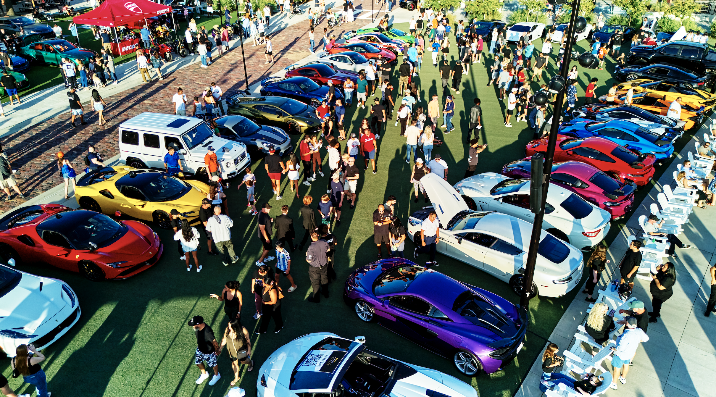 a group of people standing in a parking lot with cars