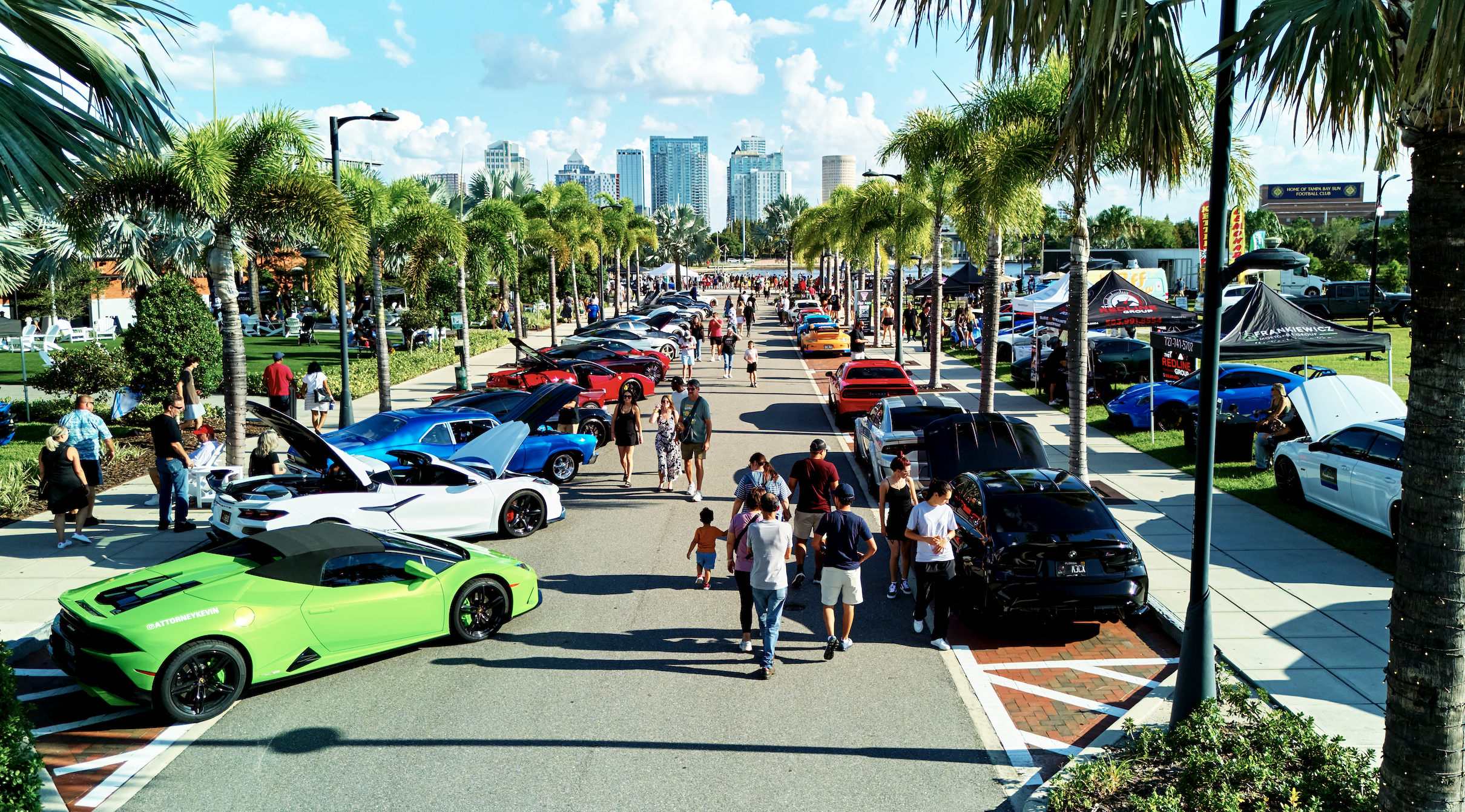 a group of people walking on a street with cars parked on the side