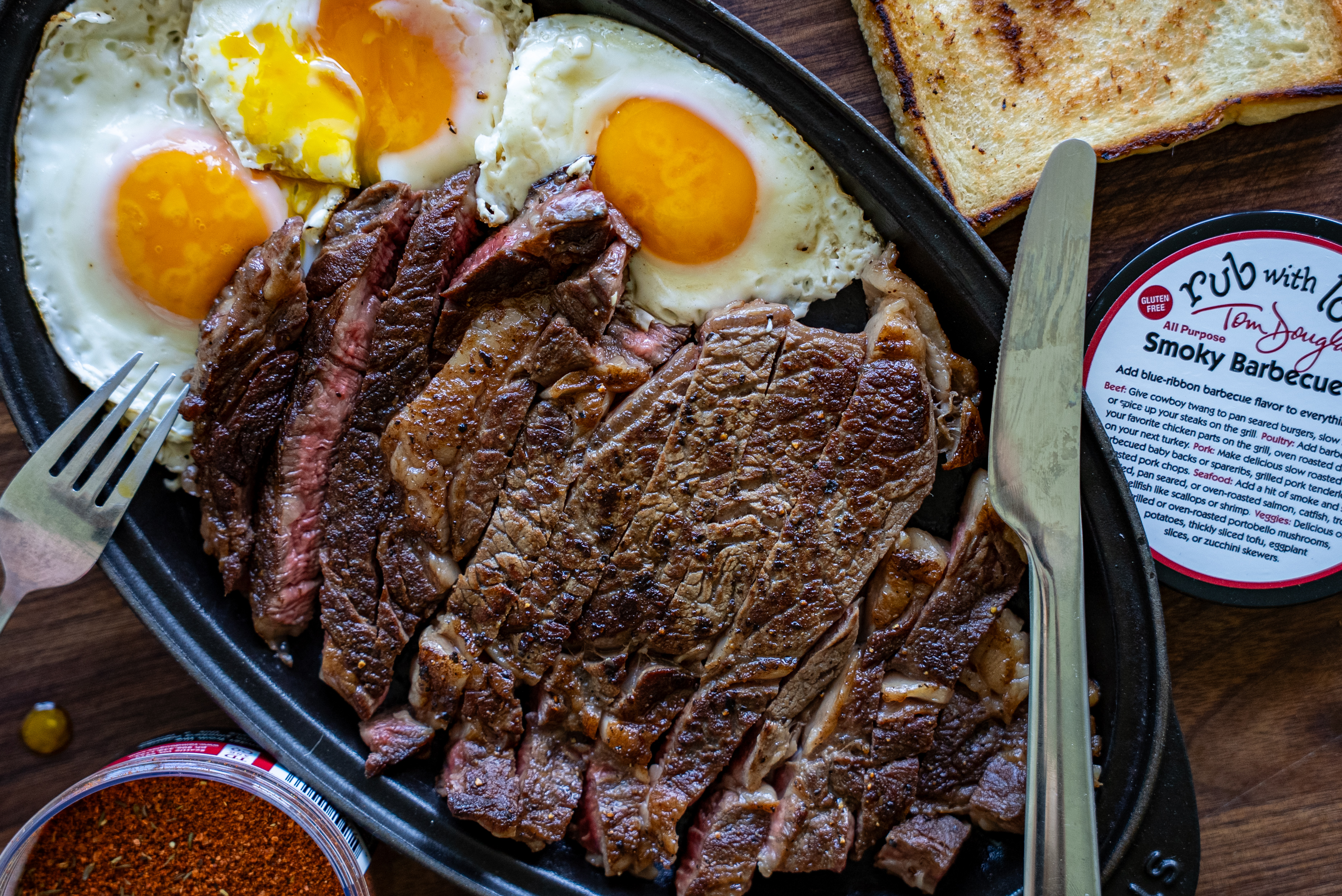 a plate of sliced ribeye steak and sunny eggs with smoky bbq rub with lovve