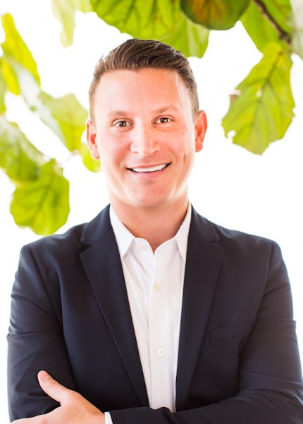a man wearing a suit and tie smiling at the camera