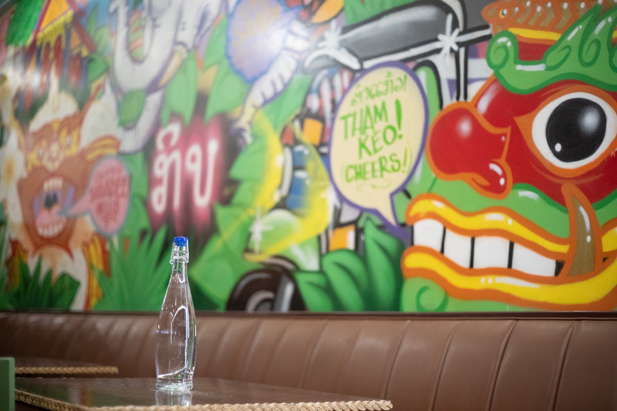 a table with a bottle of water on it in front of a mural wall