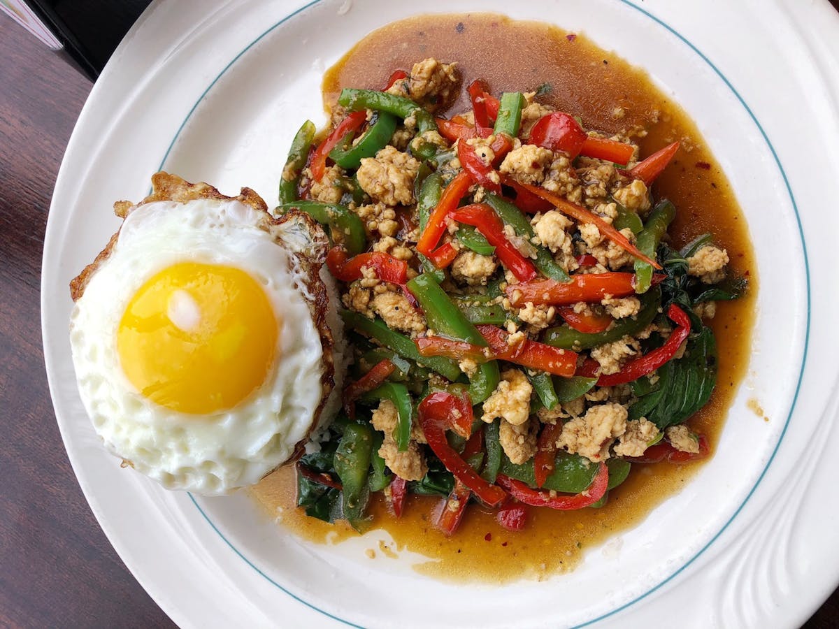 a white plate topped with meat, egg, and vegetables