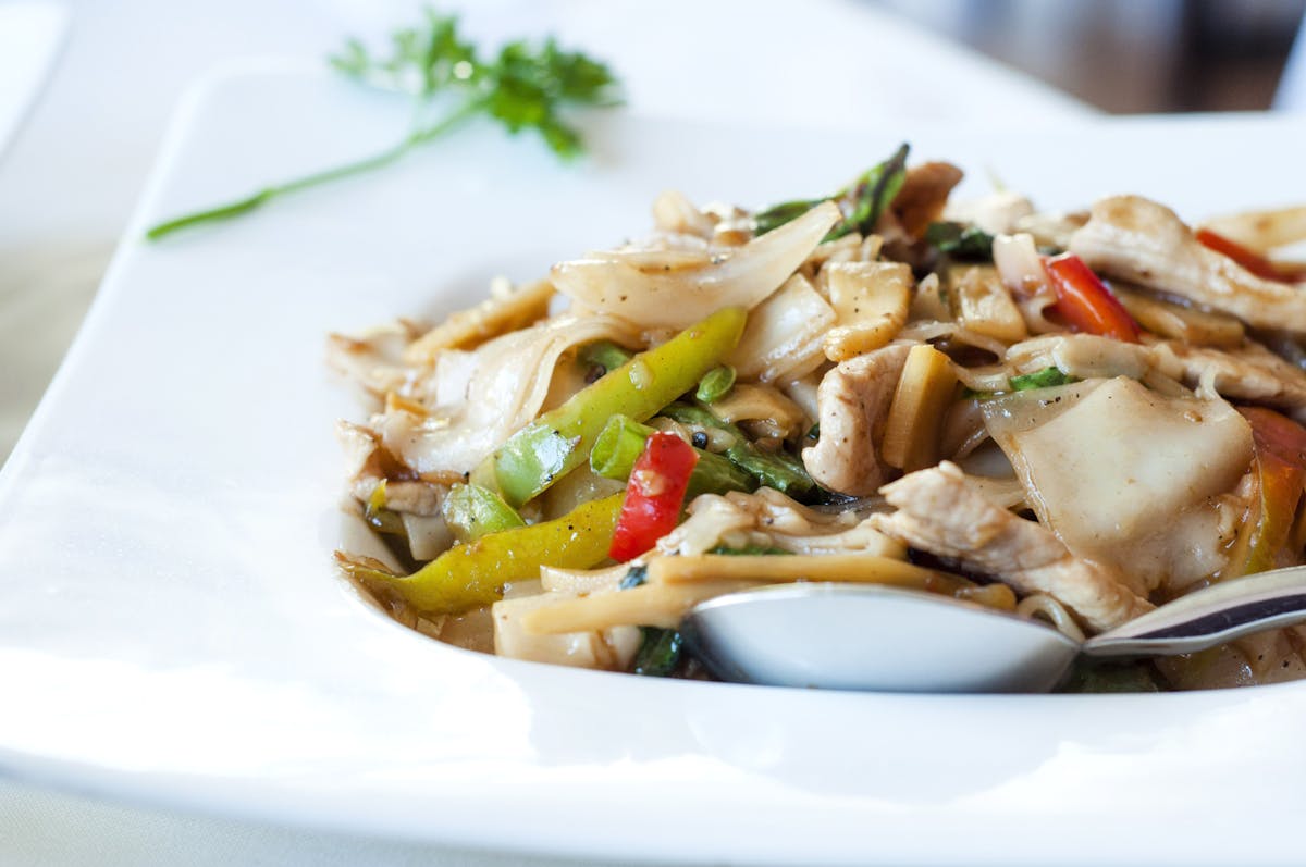 a white plate topped with shredded grilled chicken breast and vegetables
