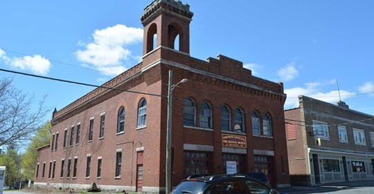a small clock tower in front of a brick building