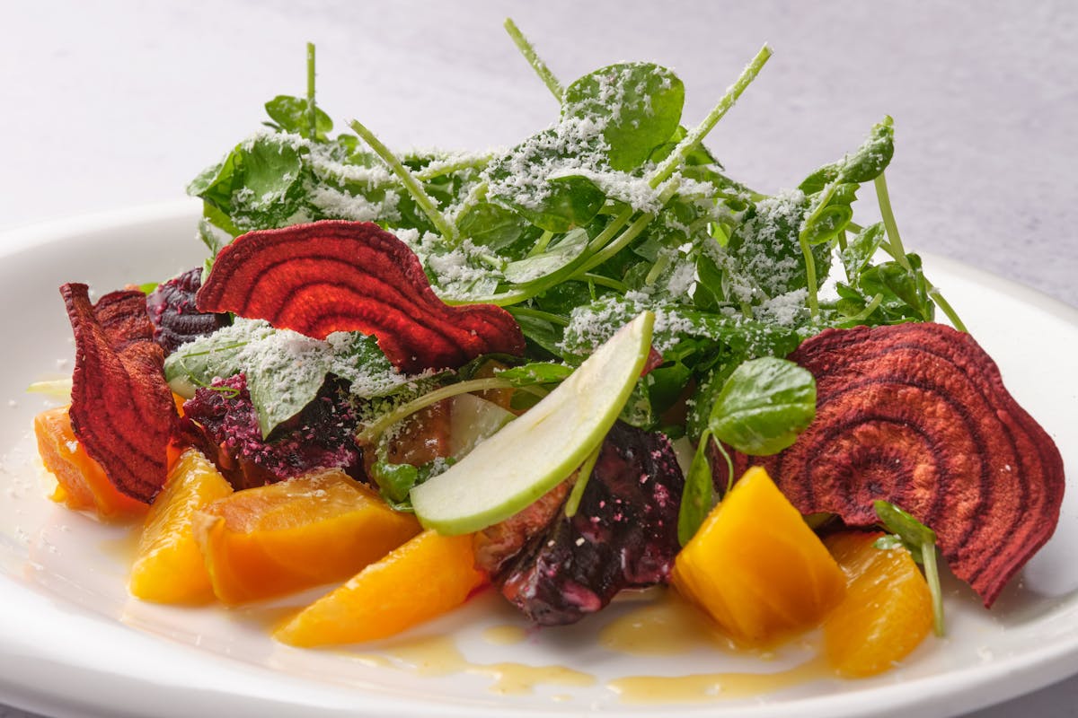 a white plate with beets, greens, and green apples.