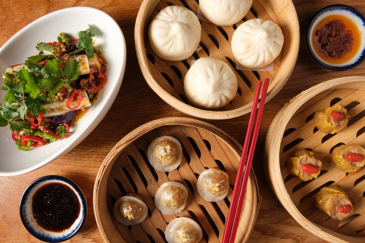 a spread of bamboo steaming baskets with dumplings and bao buns.
