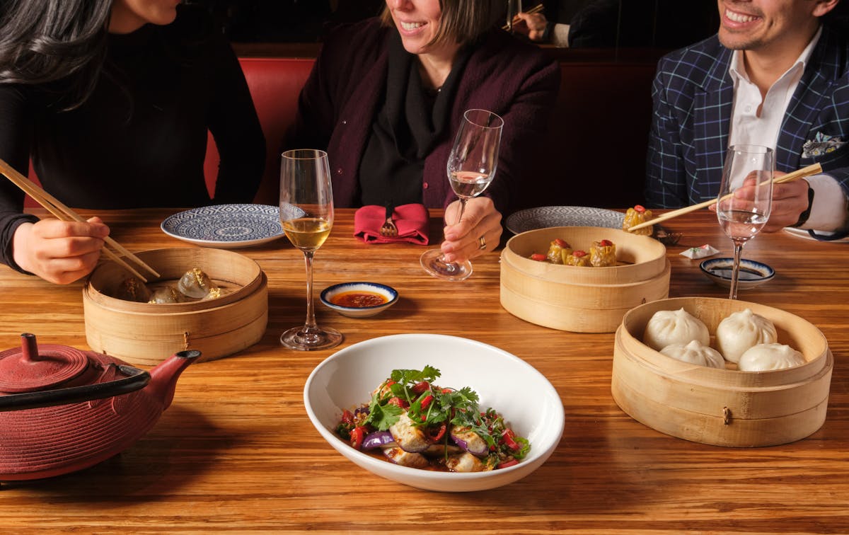 a group of people sitting at a table with plates of food.