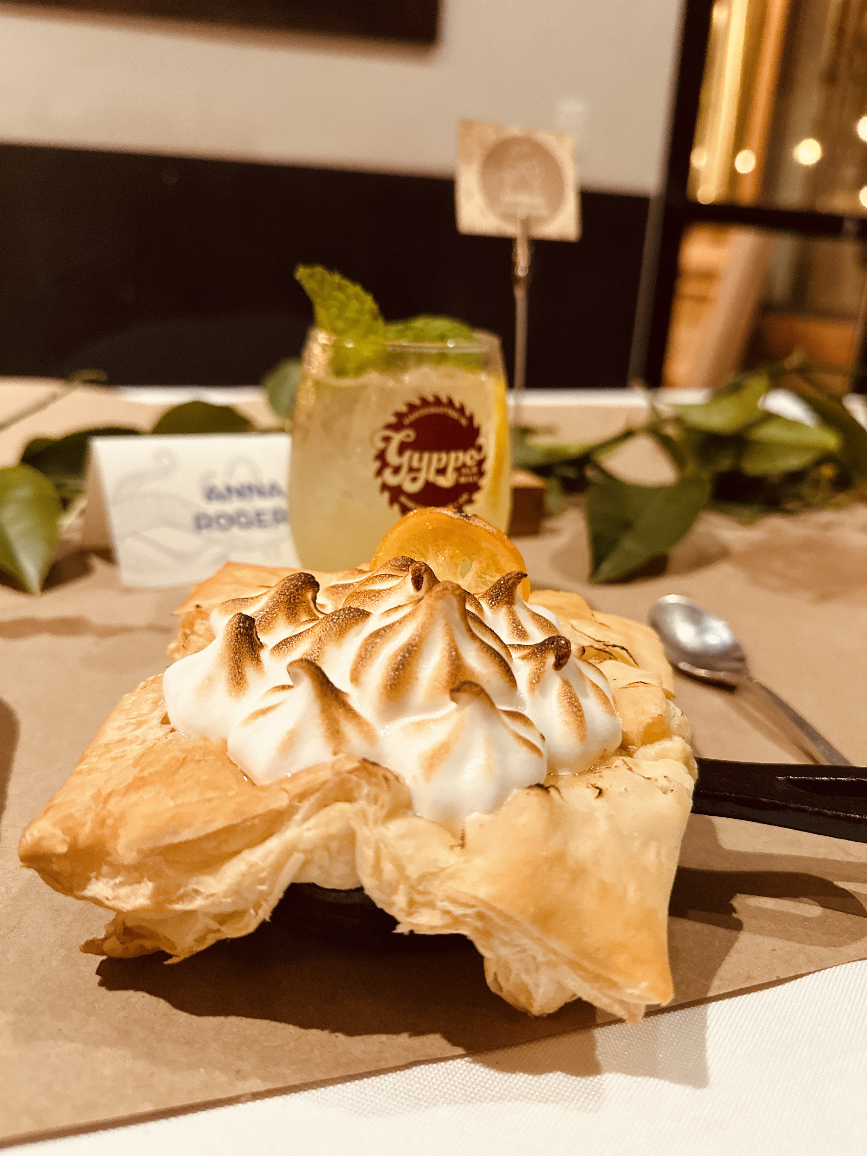 a pastry with whipped cream on top and a drink in the background