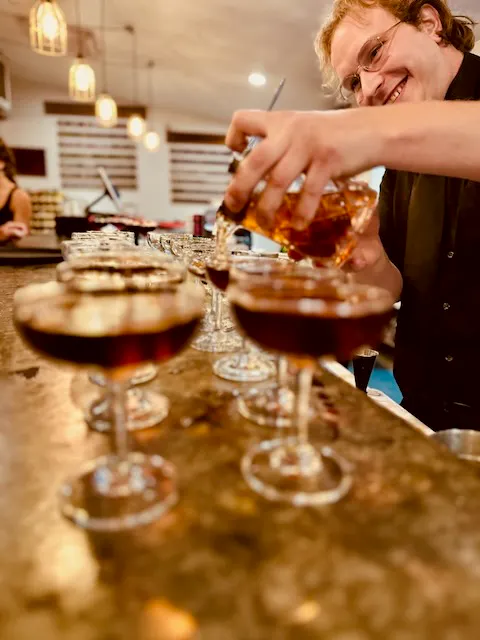 a person pouring alcohol into glasses
