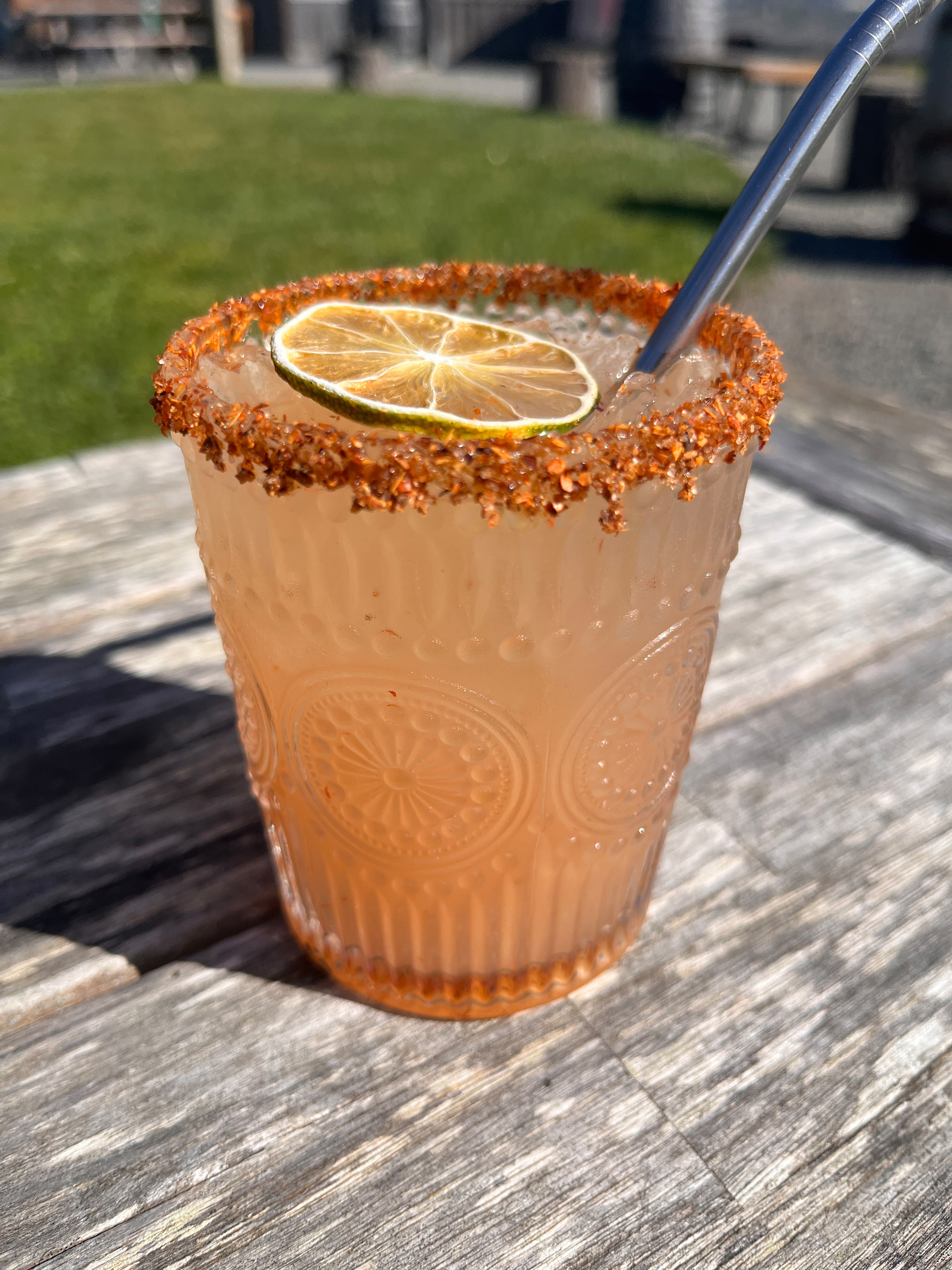 a glass with a drink and a spoon on a table