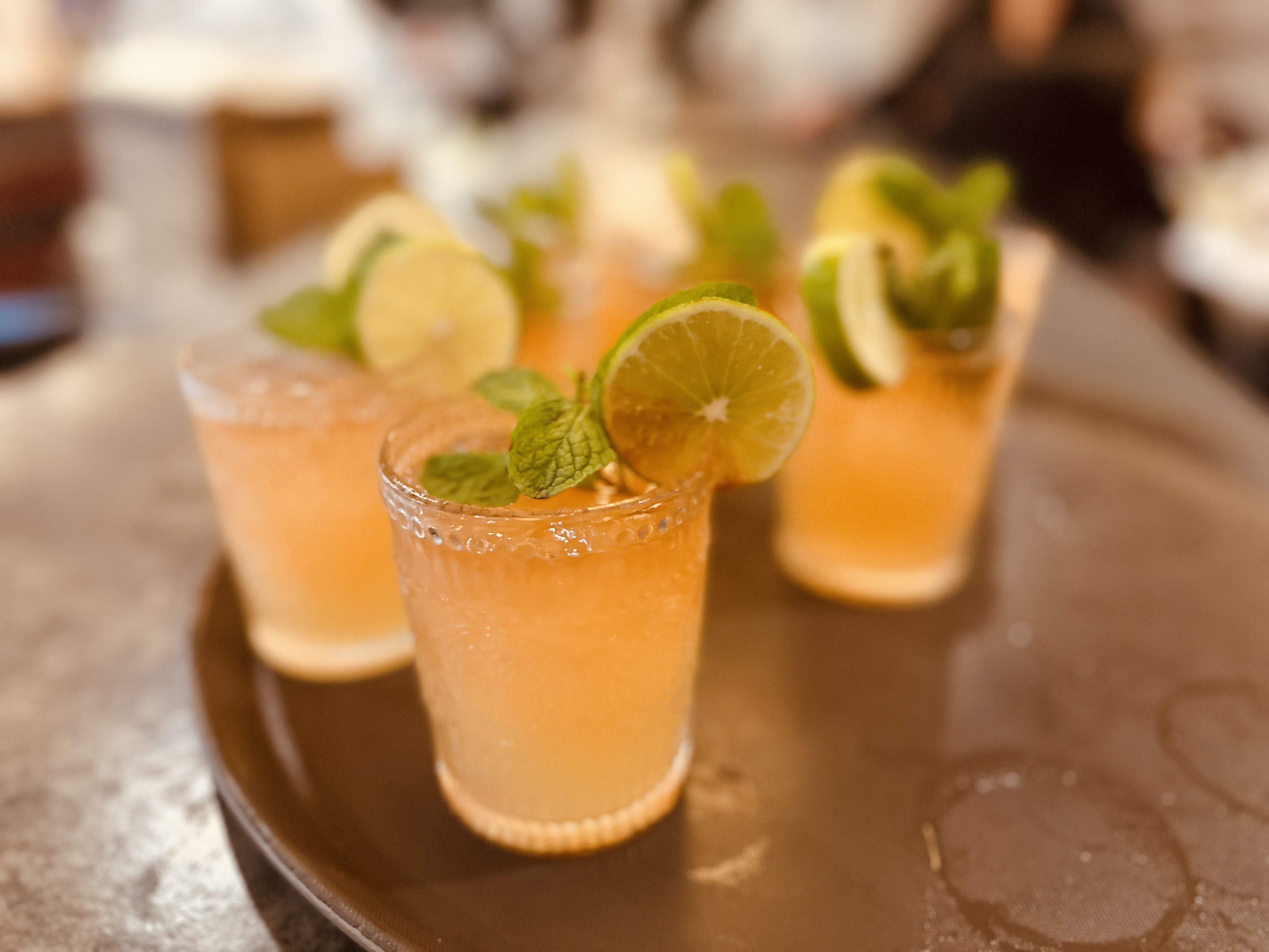 a group of glasses with liquid and limes on a tray