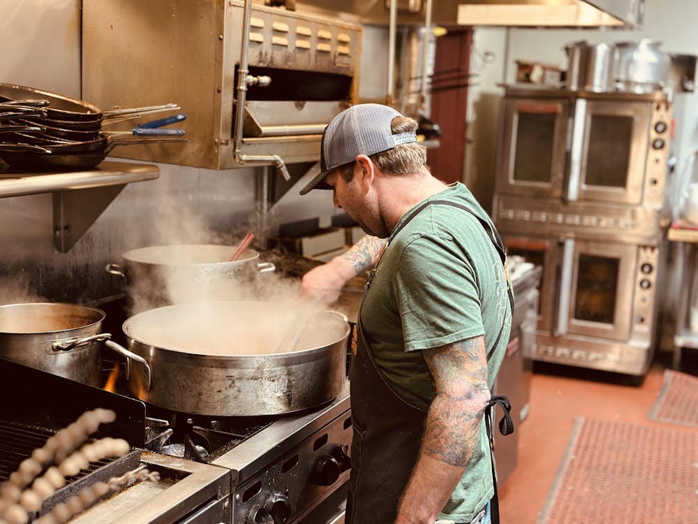 a man cooking food in a pan on a stove