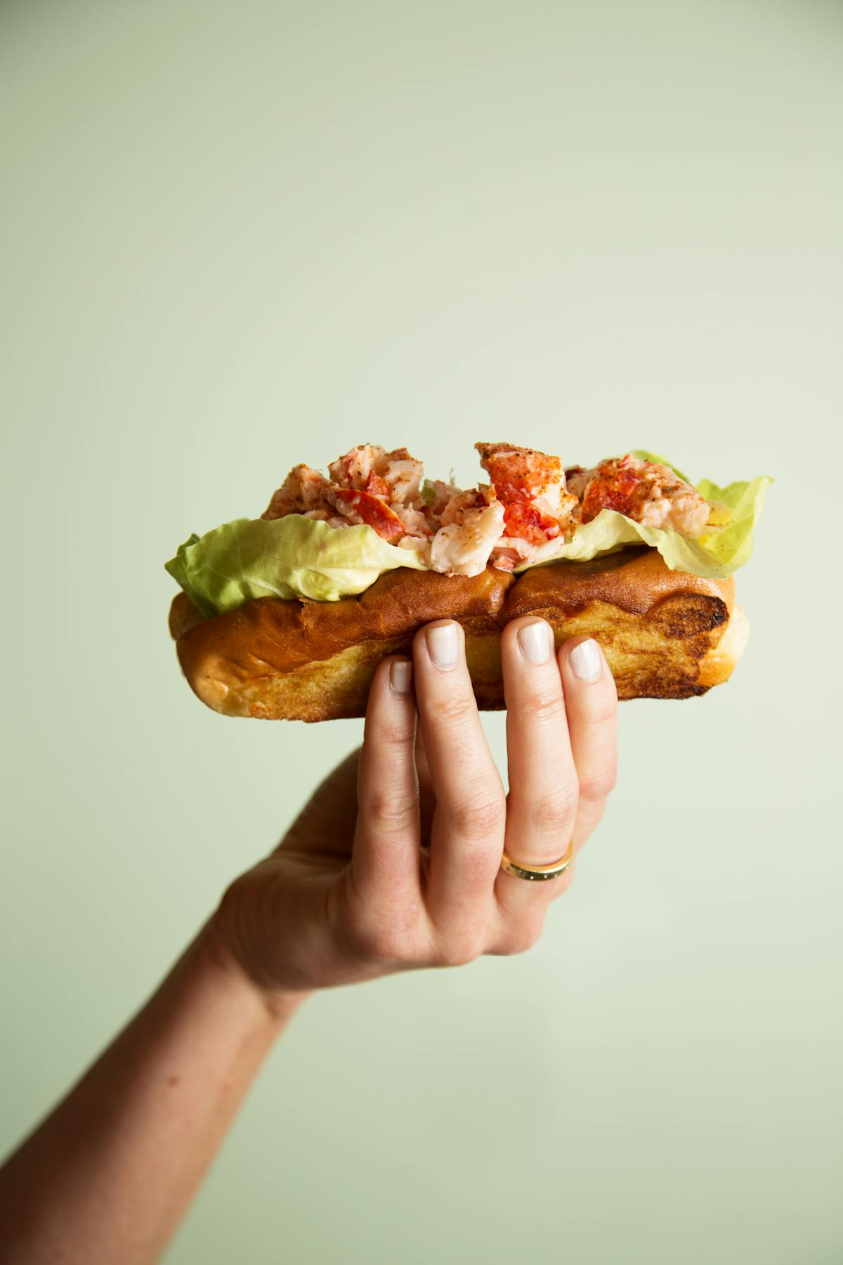 a hand holding a half eaten sandwich