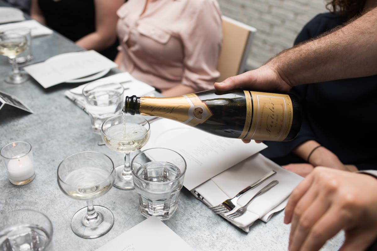 a person sitting at a table with wine glasses