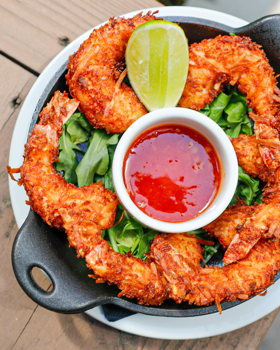 coconut shrimp in a dish with a ramekin of sauce