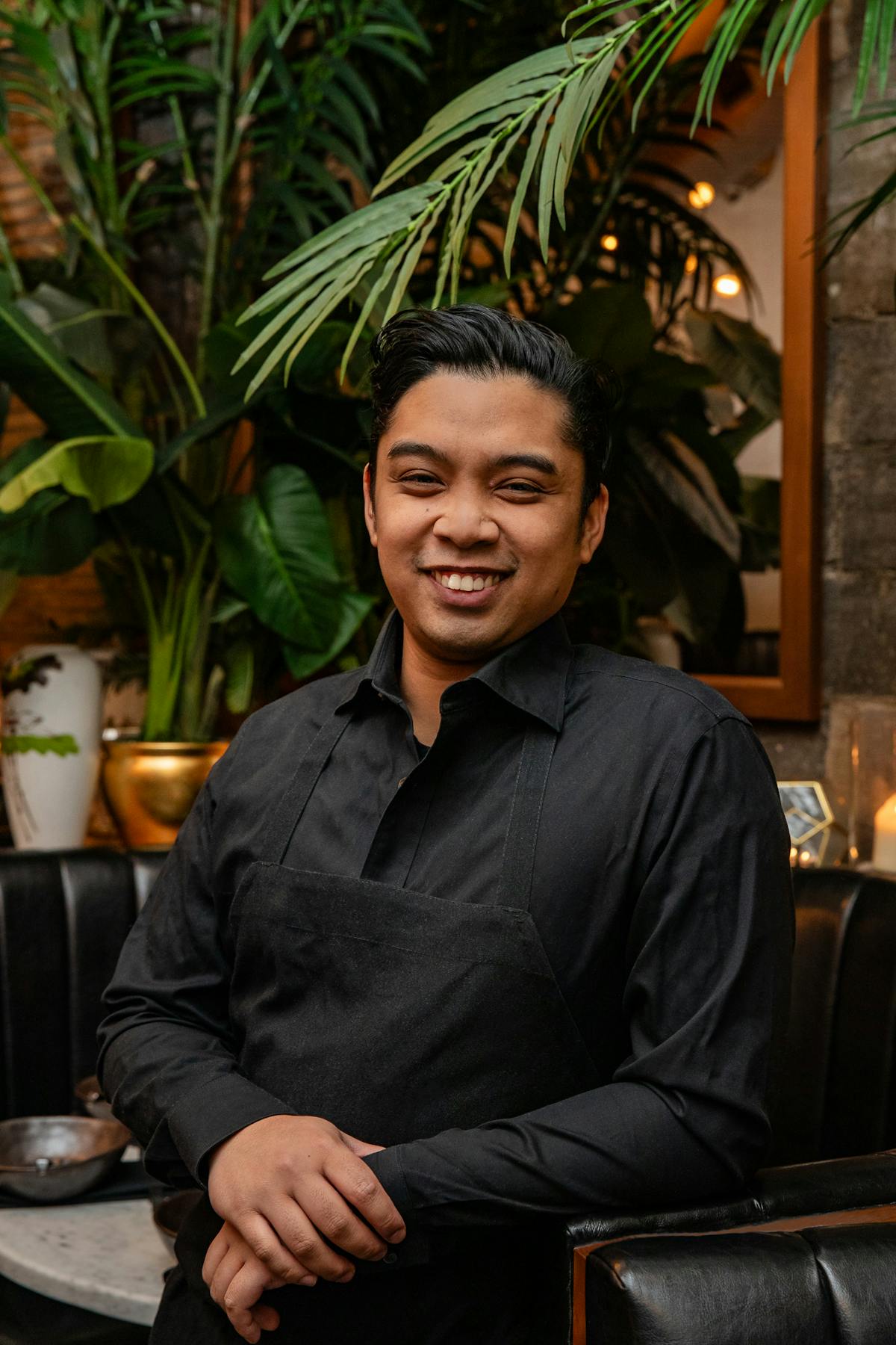 a man with short hair wearing a black apron smiling