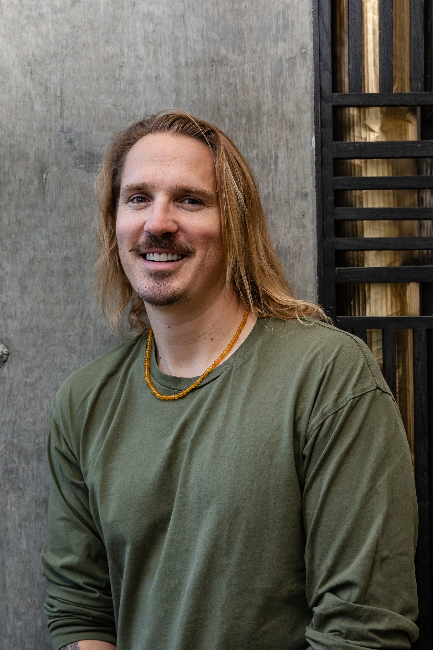 a man with long hair in a green sweater smiling