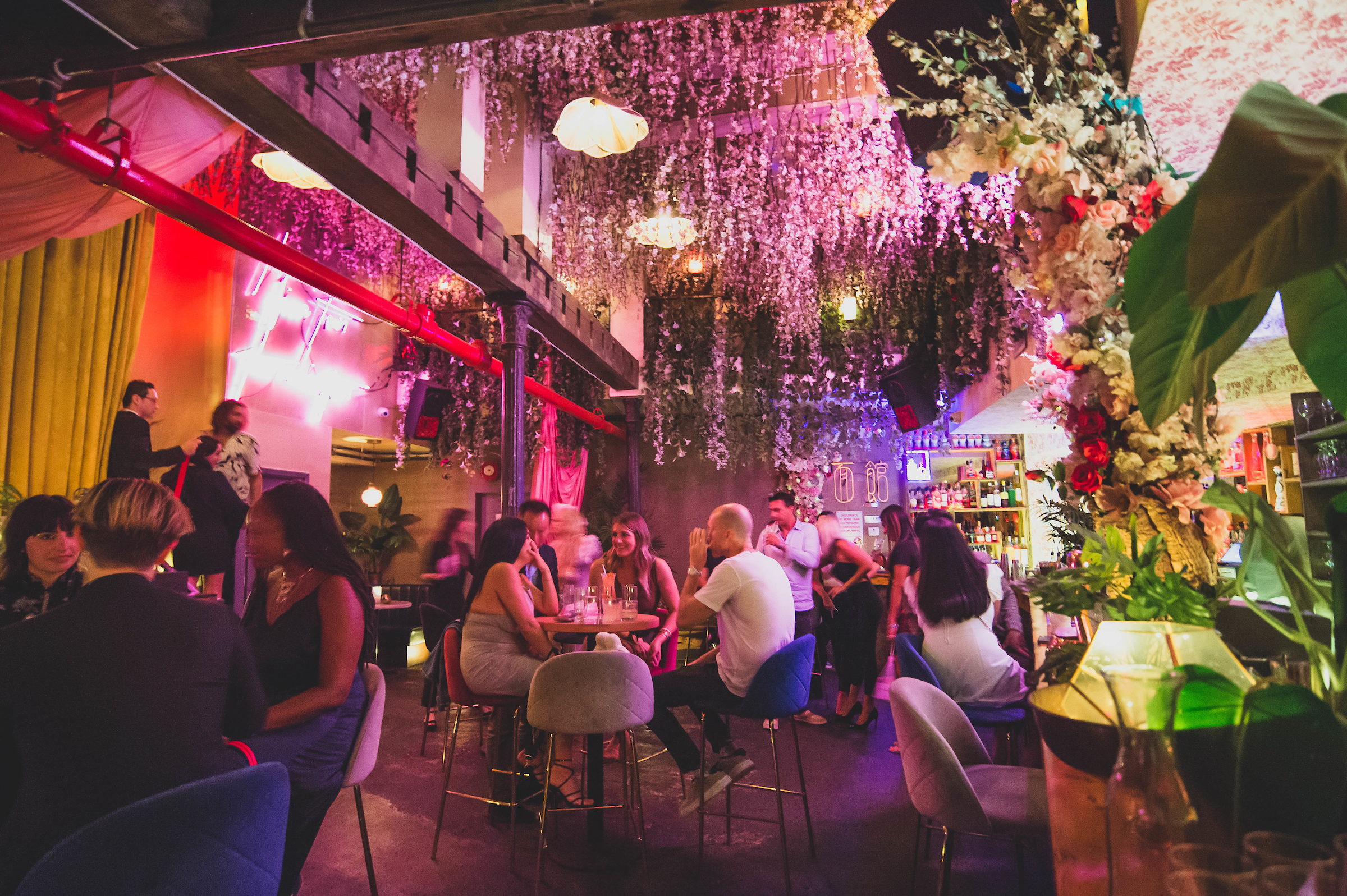 a group of people sitting at tables in a cocktail bar