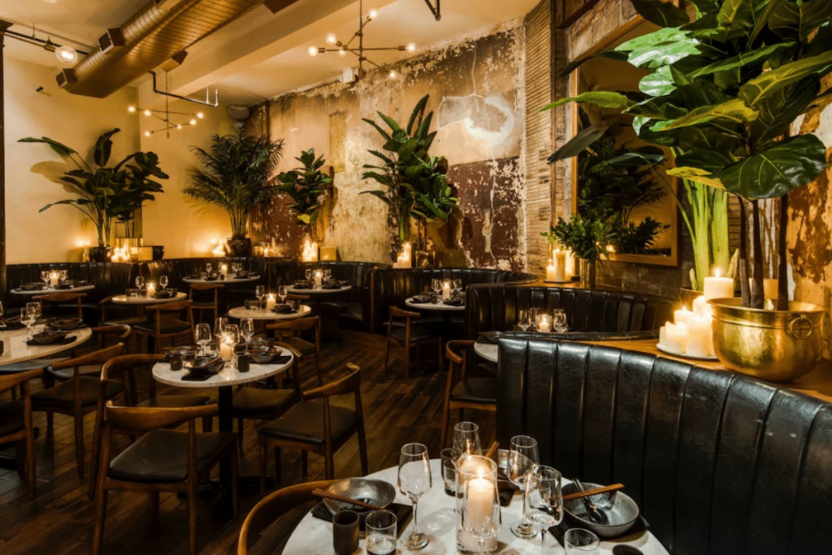 a dining room filled with plants, vases and candles