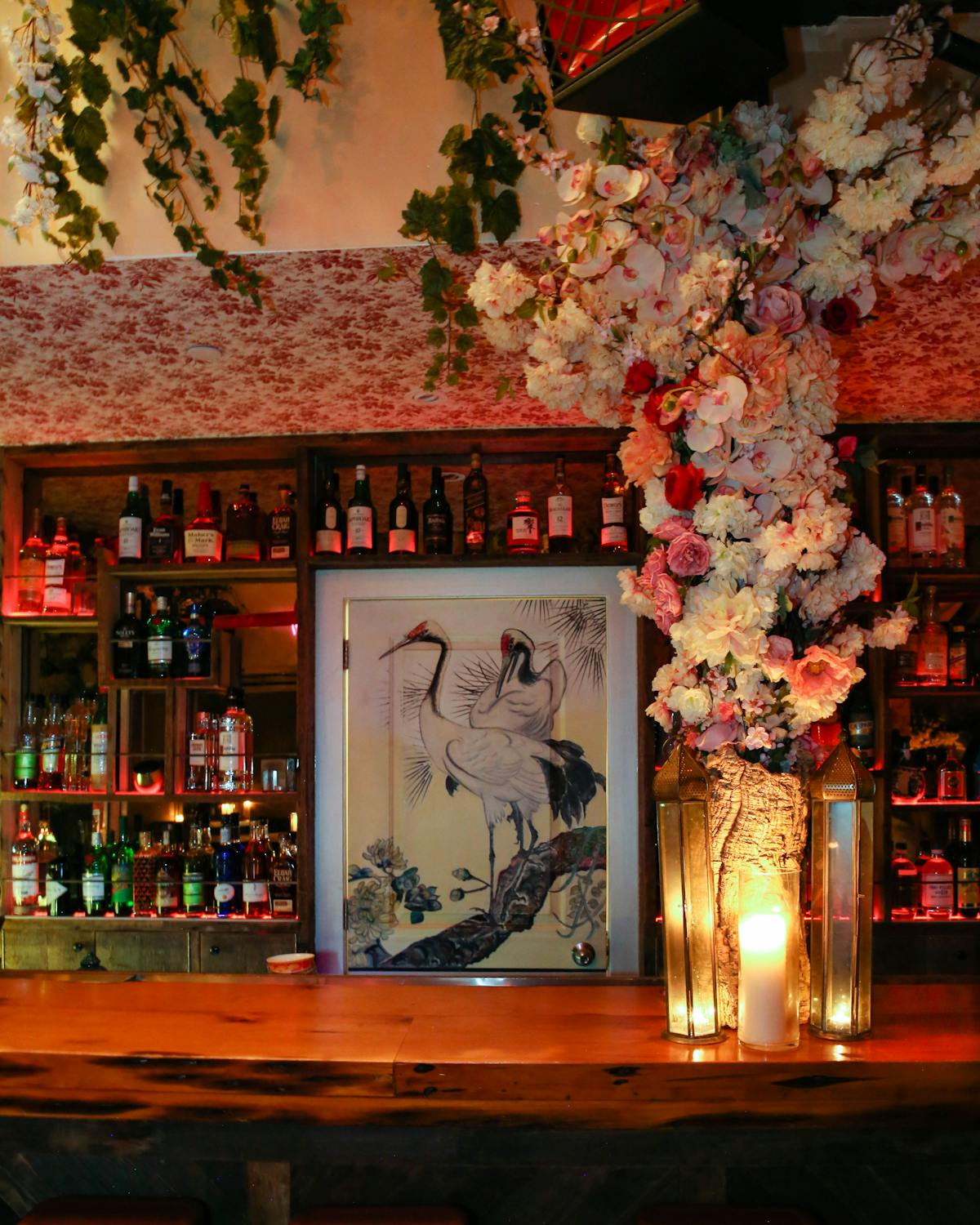 a cocktail bar with a painted door, candles, and flowers
