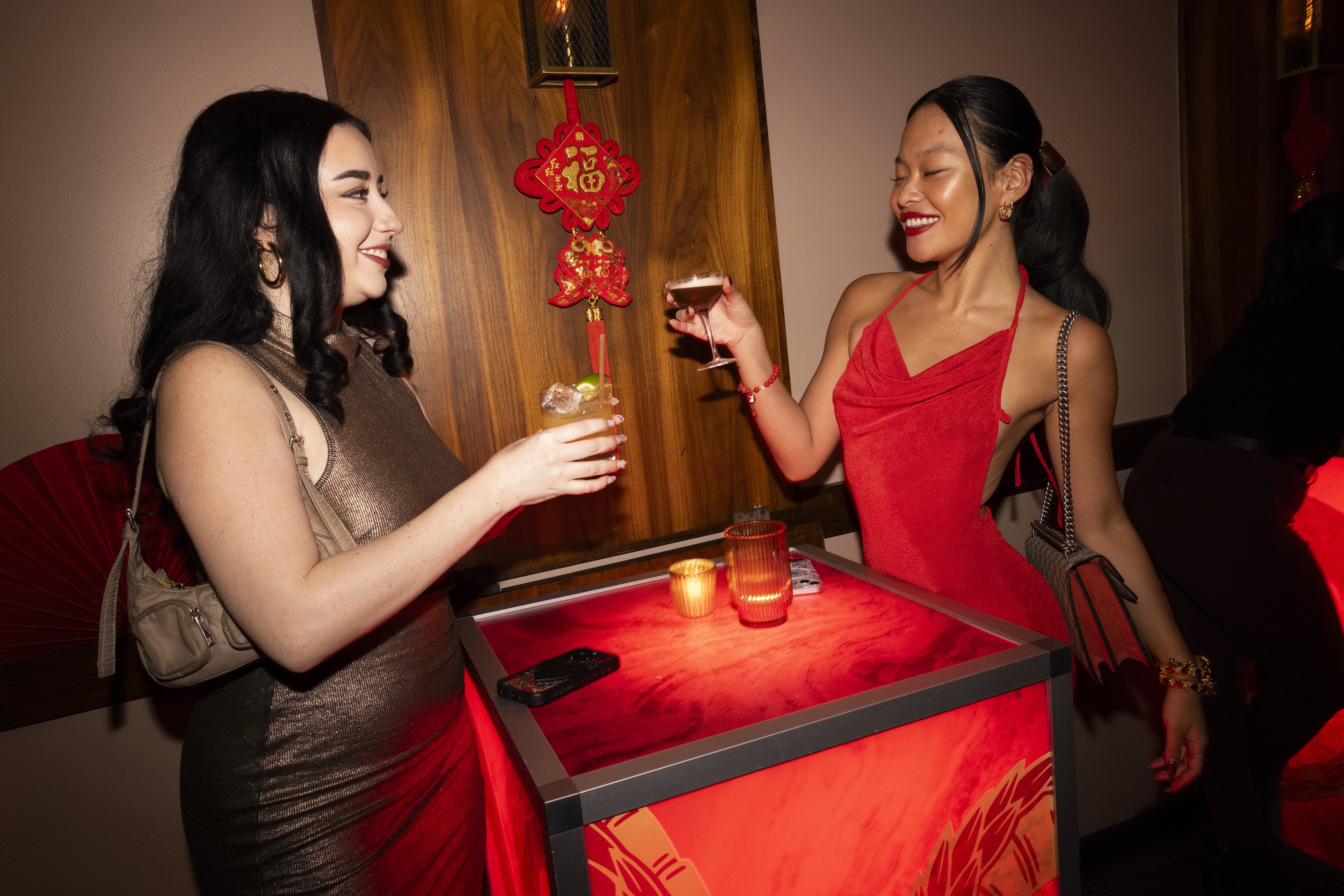 two women holding drinks and standing next to each other