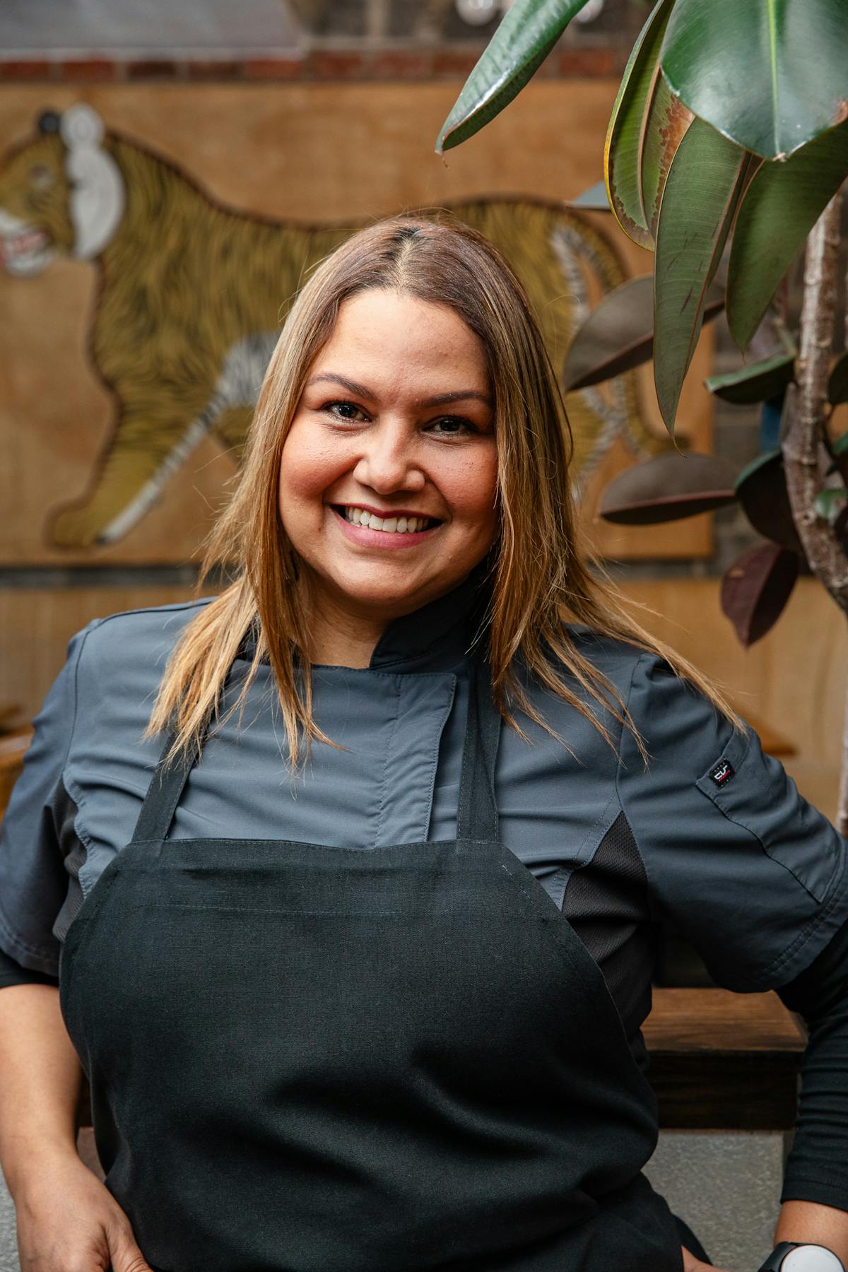 a woman with long hair wearing a black apron smiling