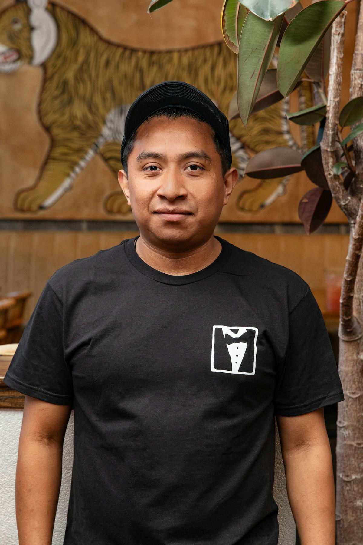 a man with a black hat wearing a black shirt smiling