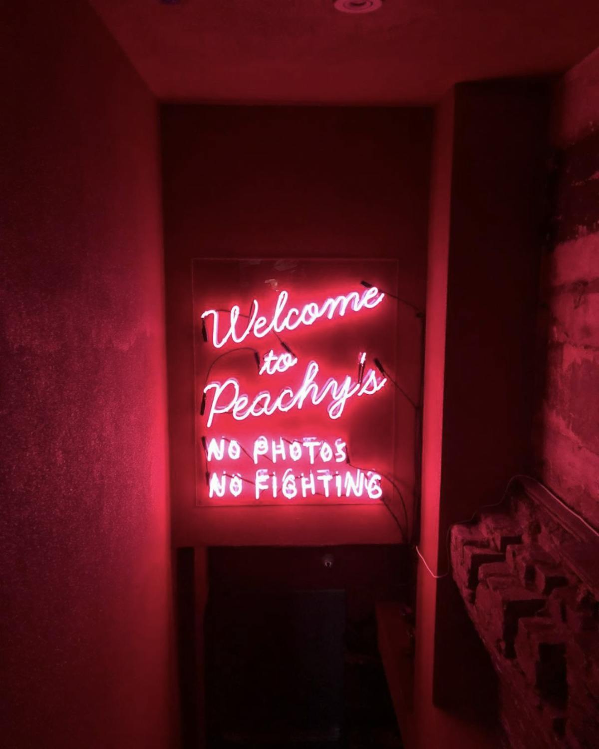 a pink neon sign in a stairway