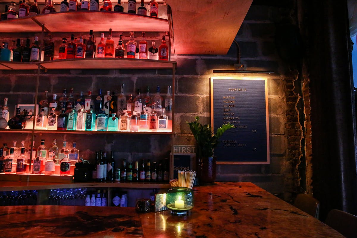 a cocktail bar with multi colored lights, stools, and burl bar