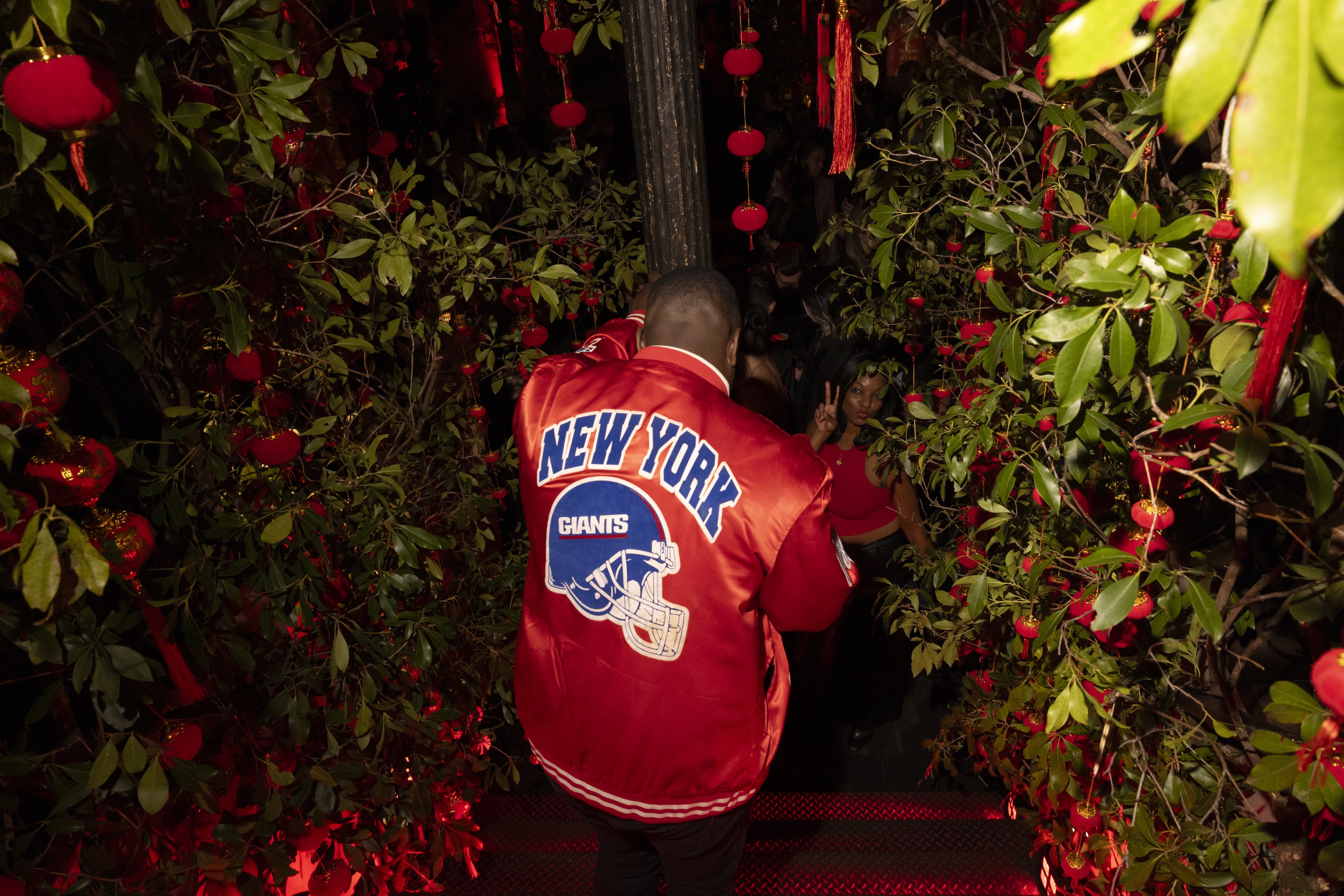 a man in a red jacket walking down a path between bushes