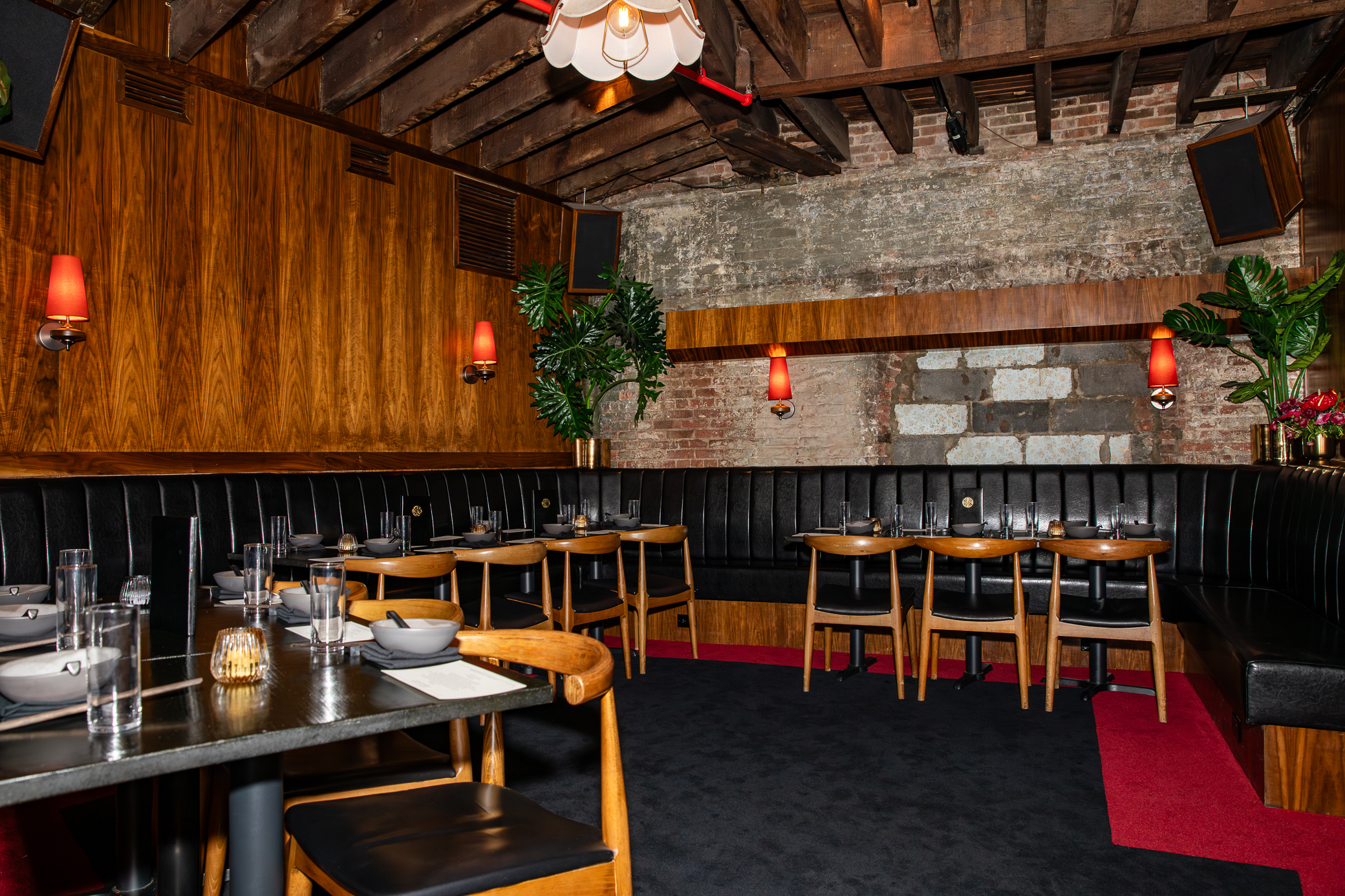 a room with a booth set up and a table with chairs and a red rug