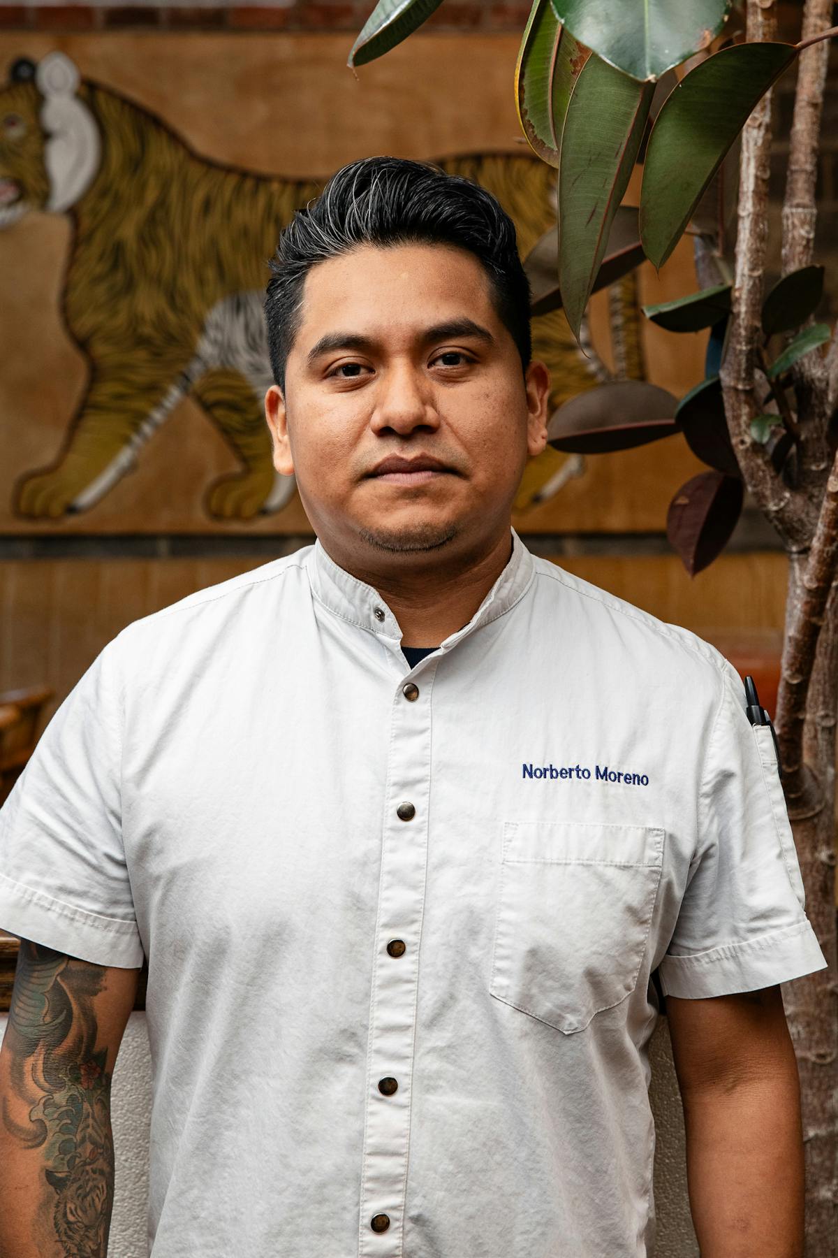 a man with short hair wearing a white chef's jacket smiling