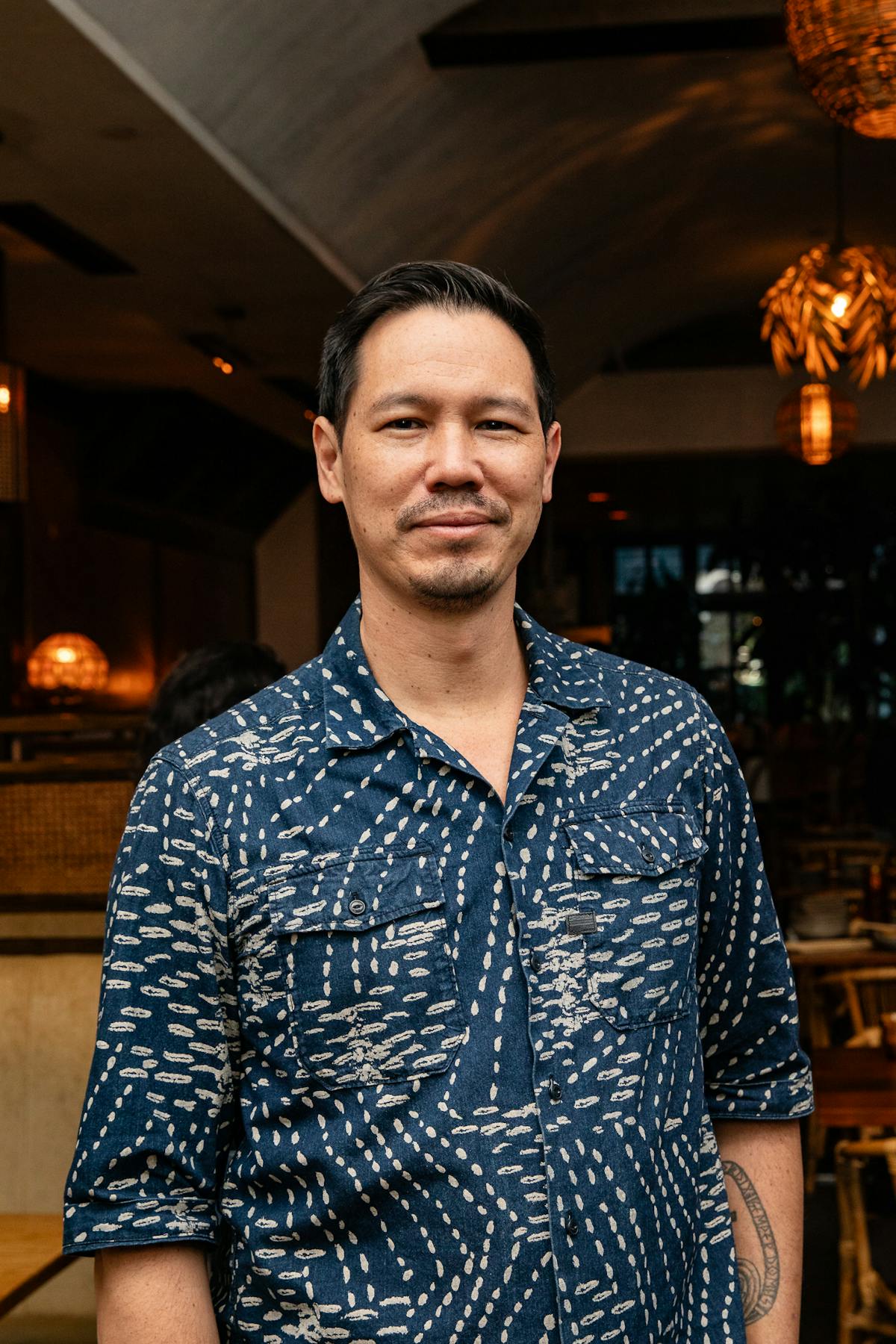 a man with short hair in a blue printed shirt smiling
